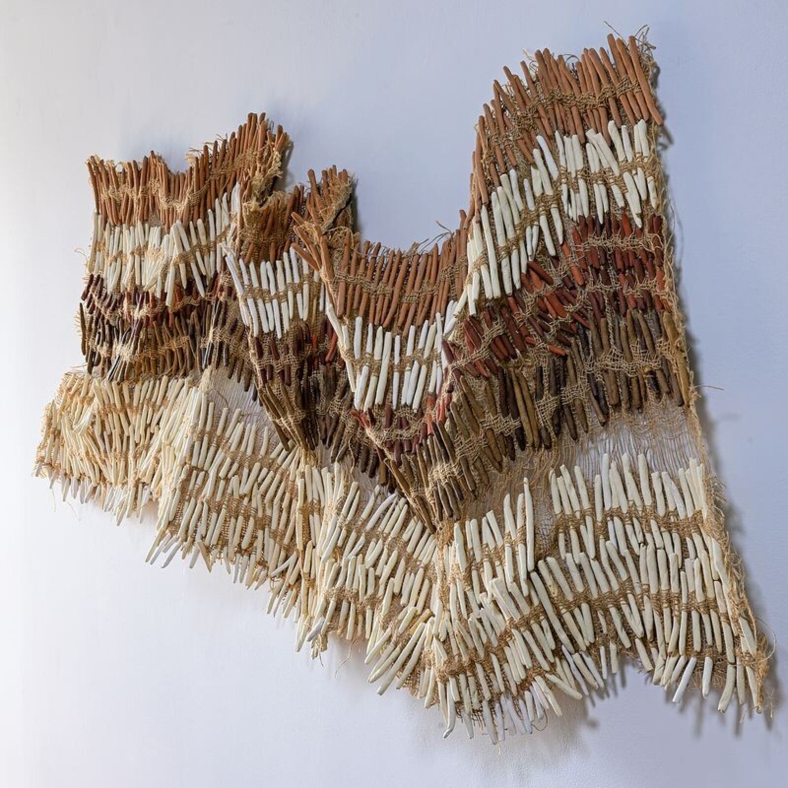 A textured wall art piece made of natural fibers with a wavy, layered design.