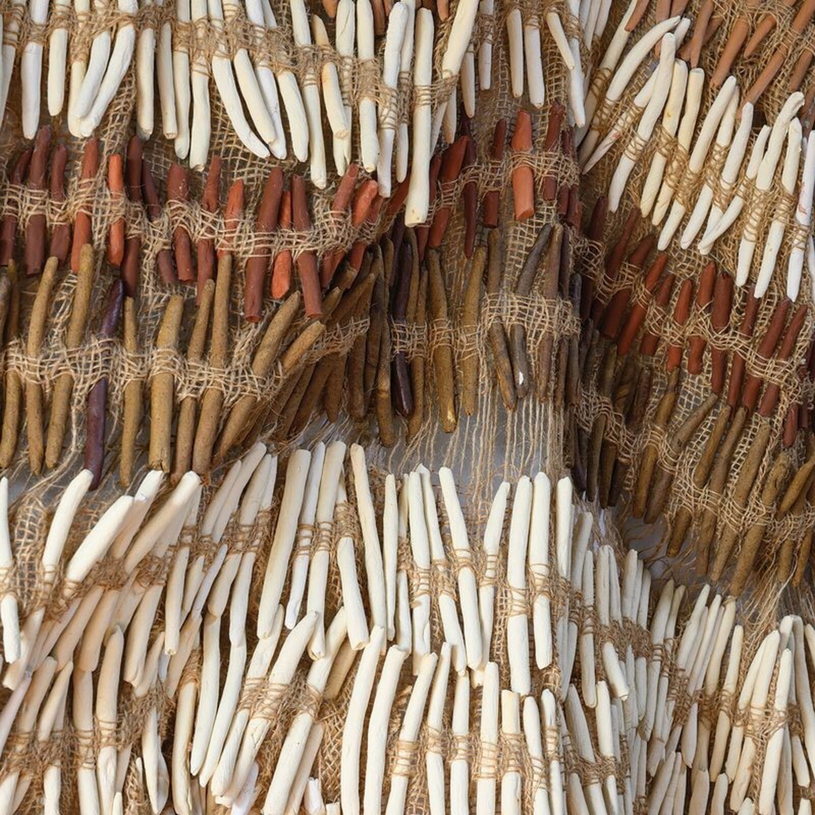A textured wall art piece made of natural fibers with a wavy, layered design.
