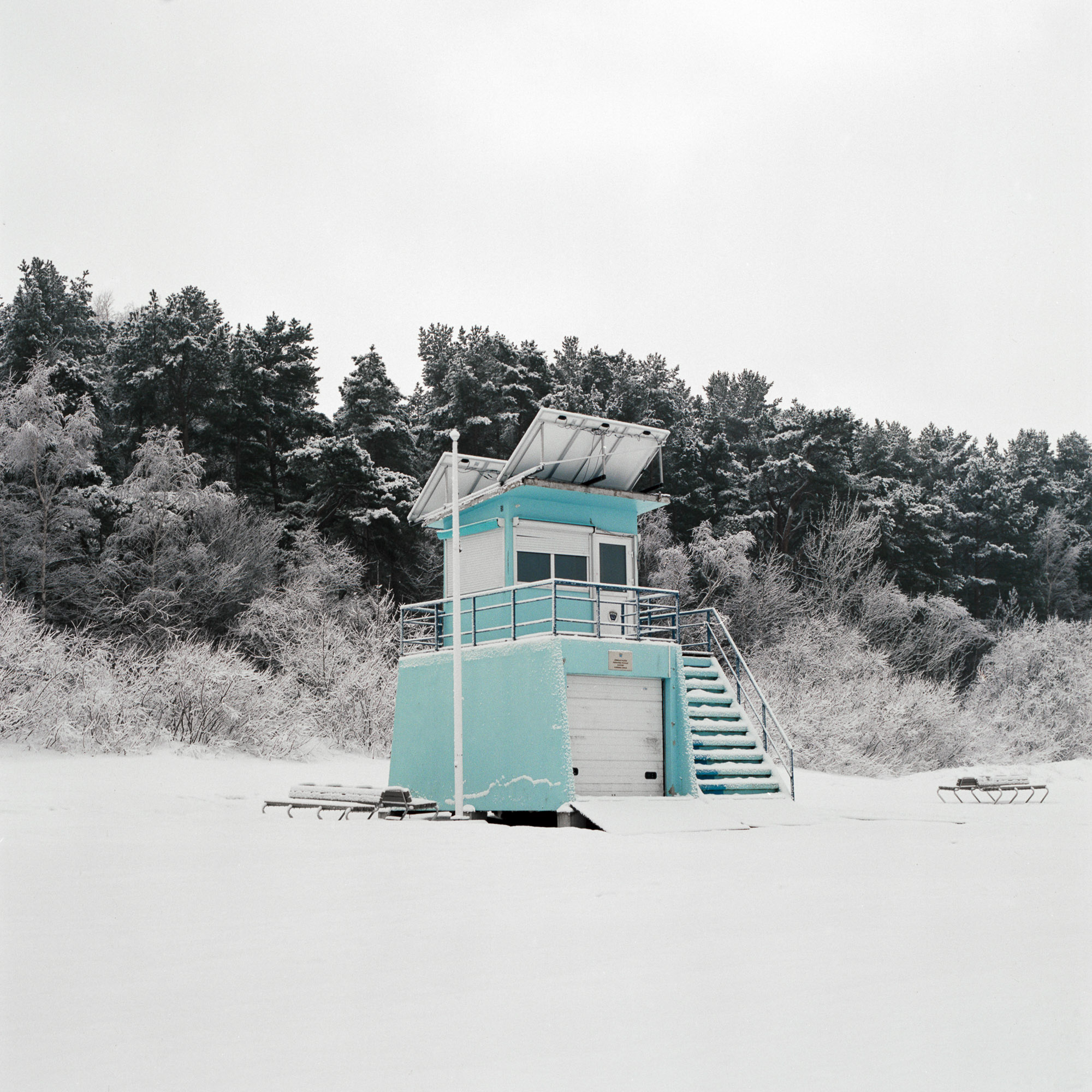 A blue and white building sitting in the middle of a snow covered field.