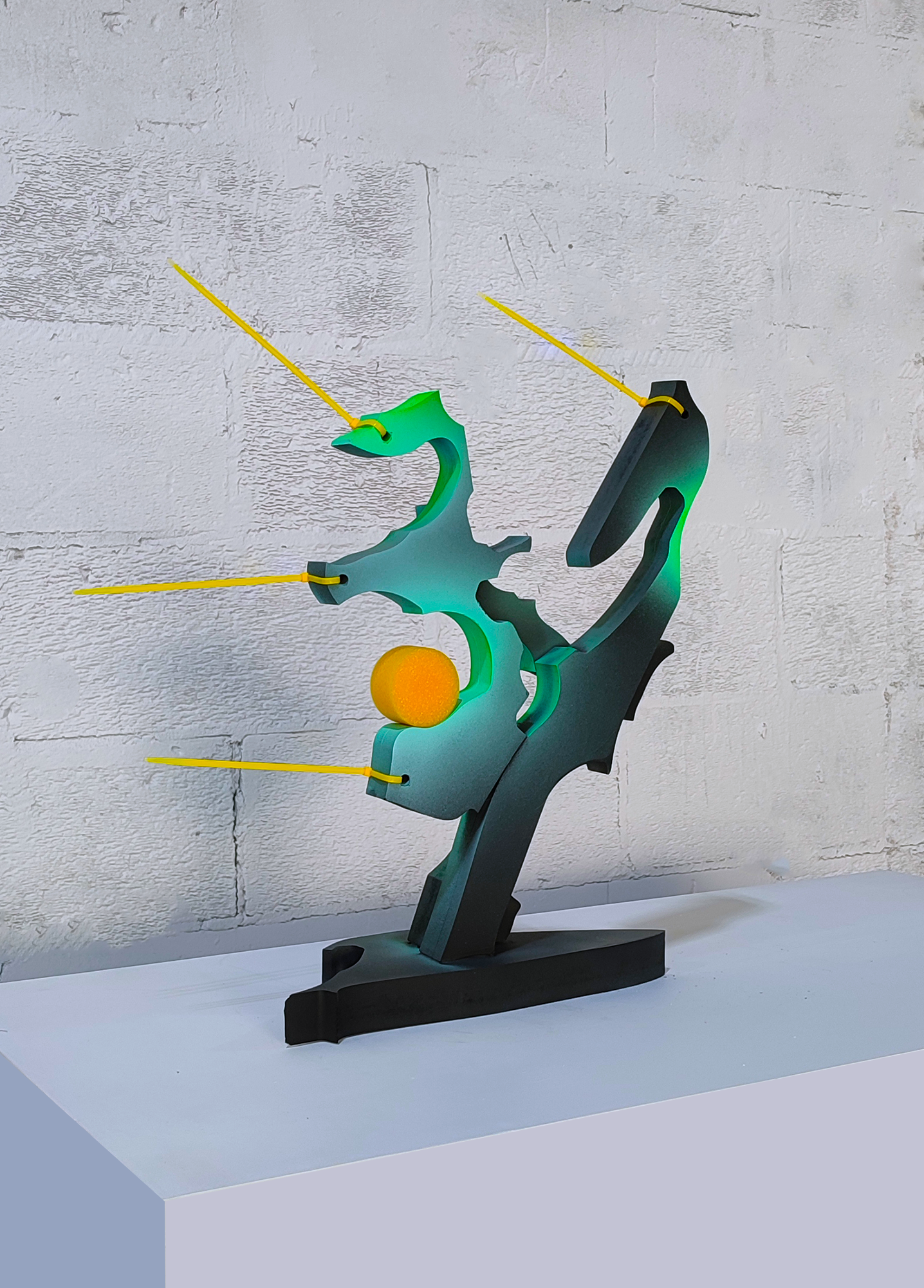 A sculpture of a seahorse holding an orange on a white surface.