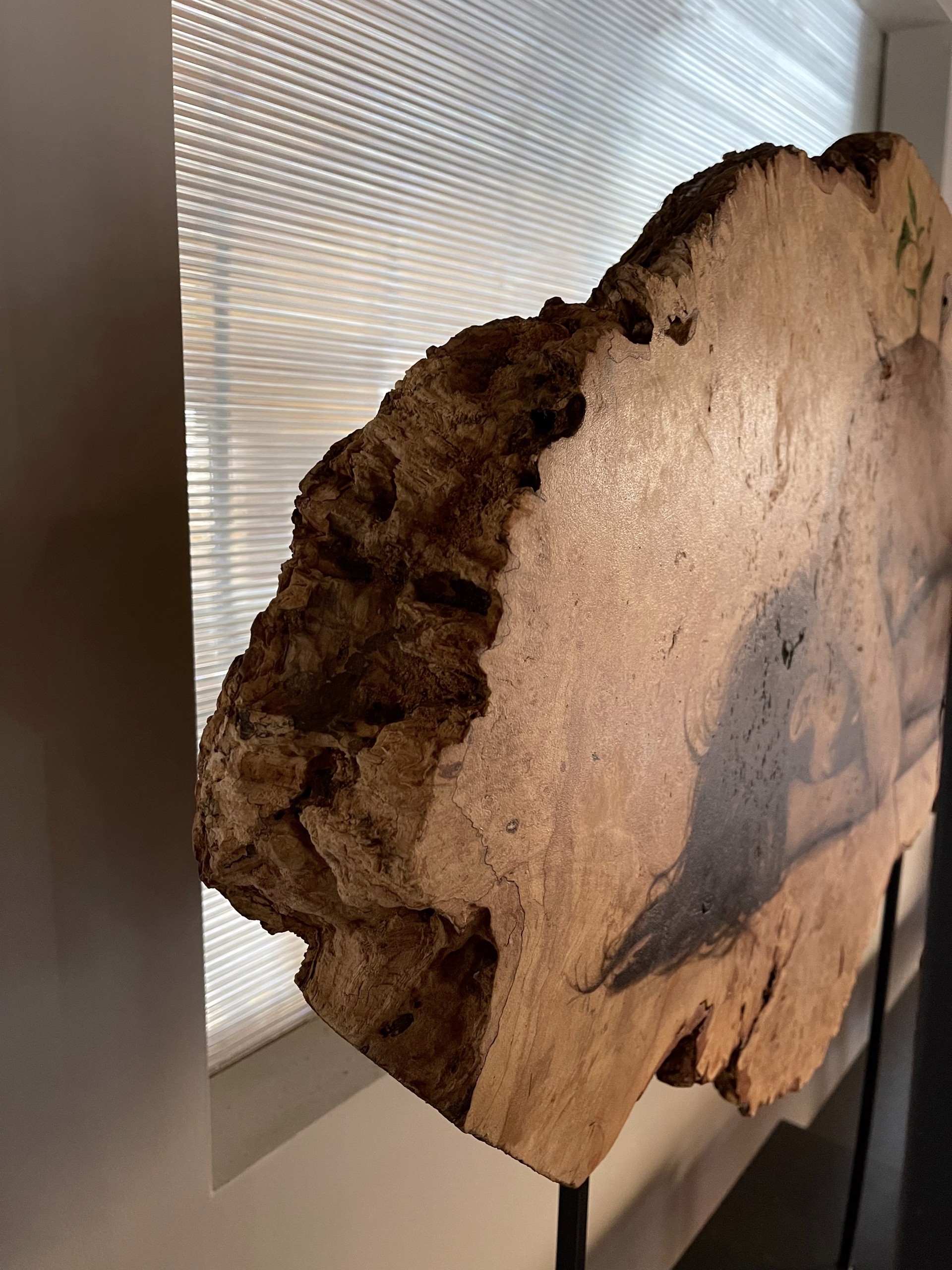 A sculpture of a woman laying down on a piece of wood.