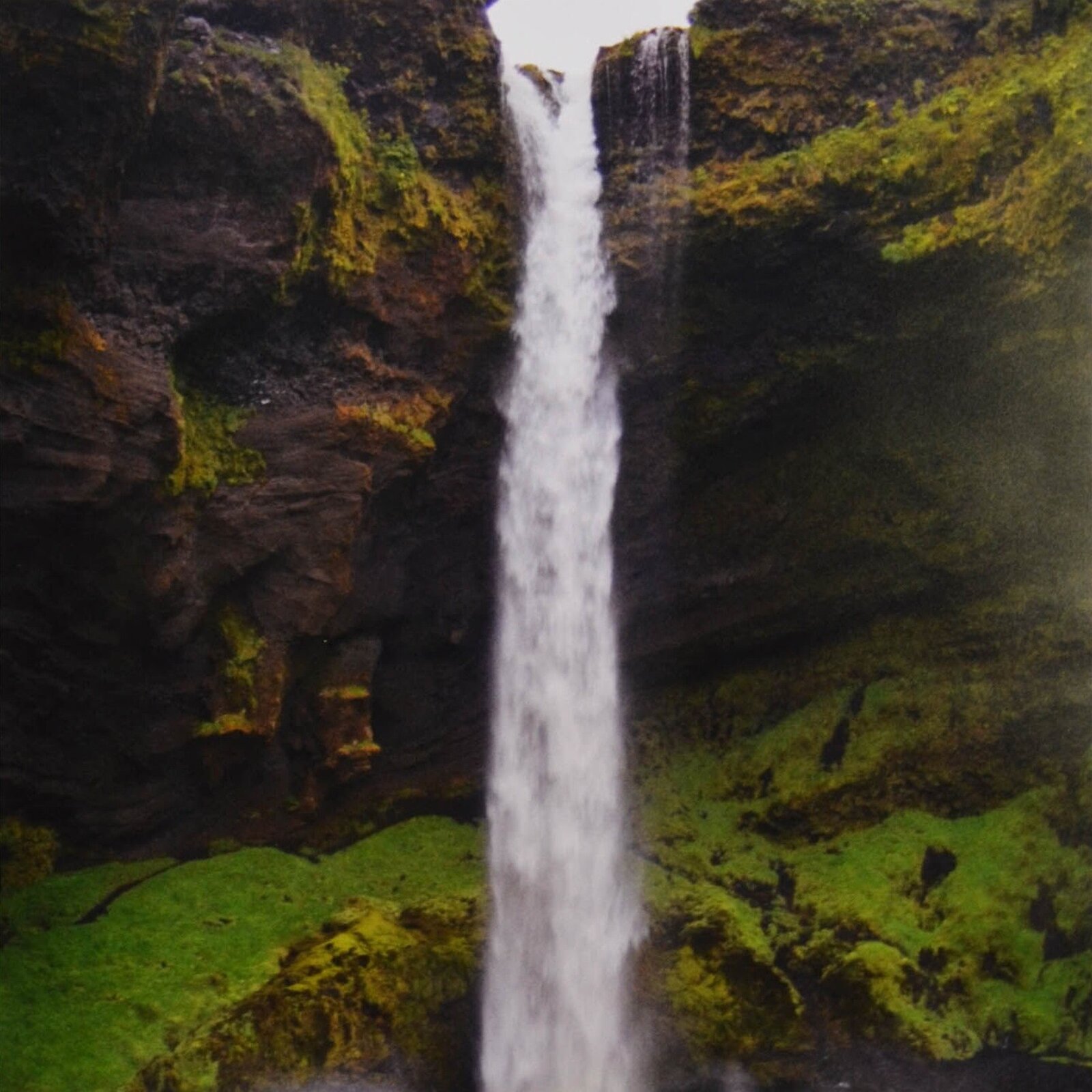 A split-panel framed artwork of a waterfall cascading over mossy rocks.