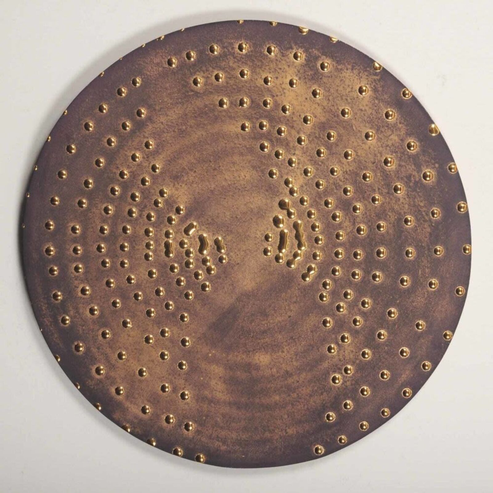 A circular metal plate with holes in it. 