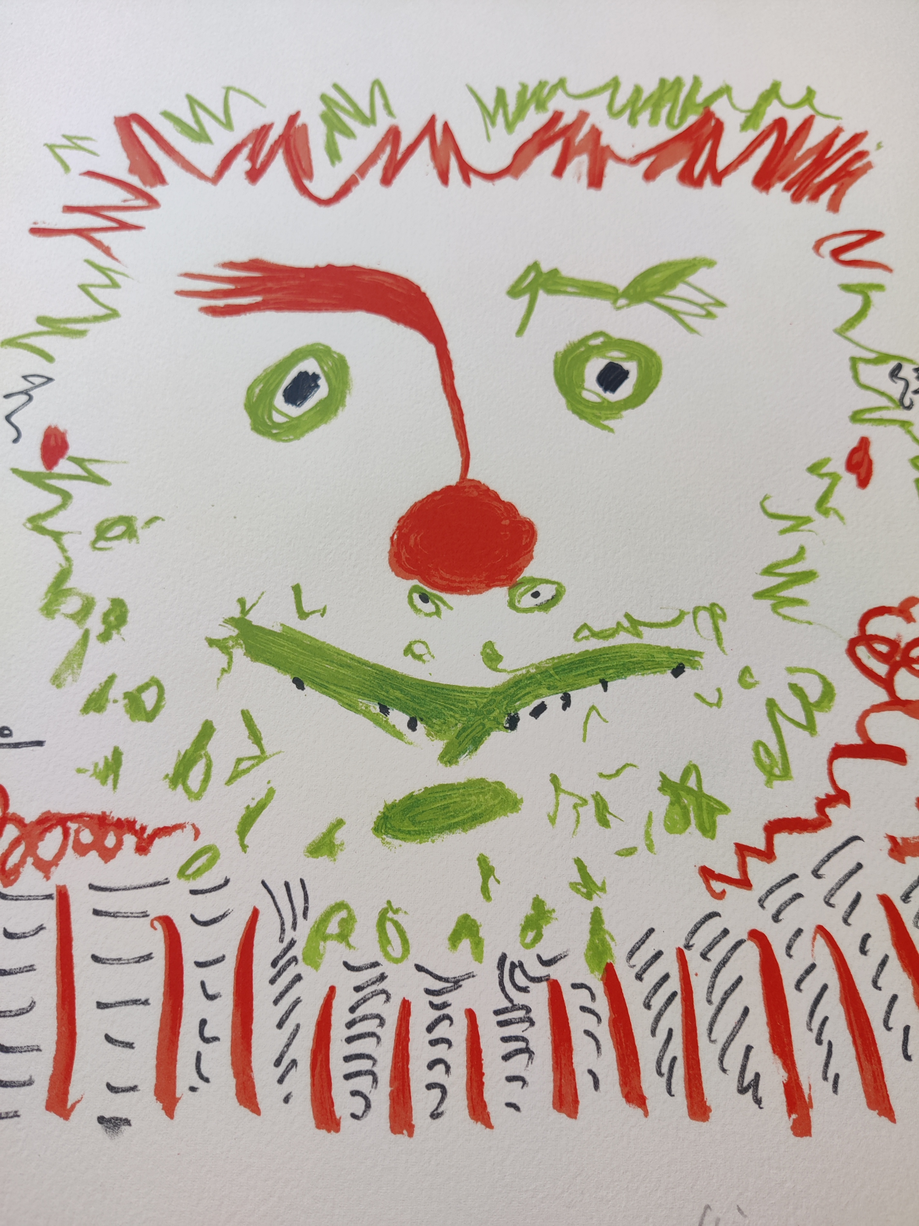 A framed picture of a clown face in a gold frame.