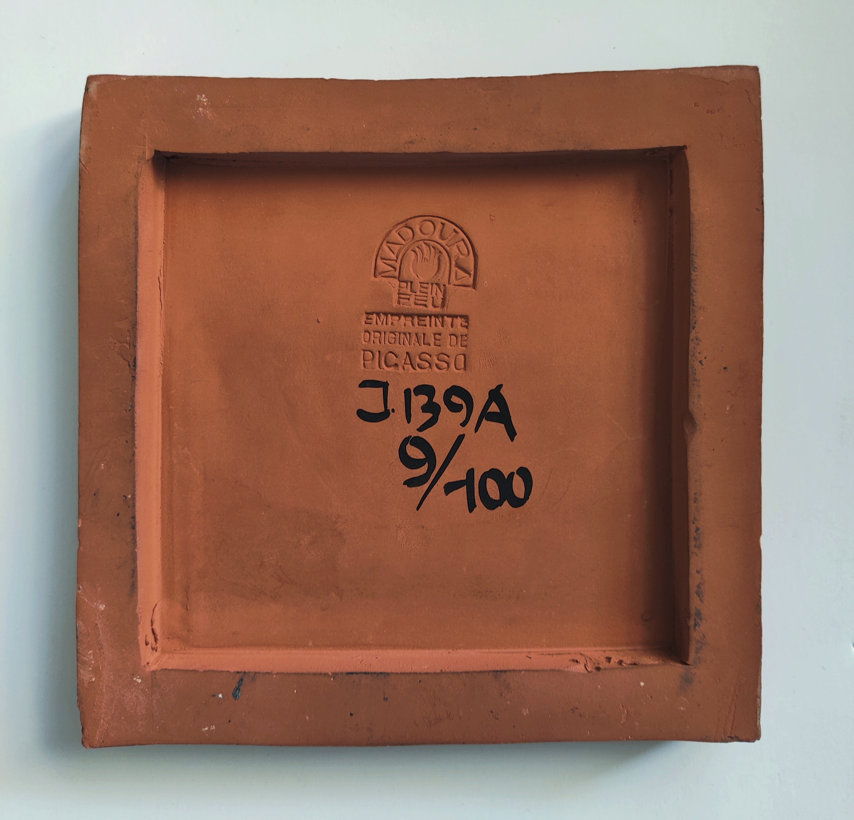 A ceramic tile with a face painted on it.