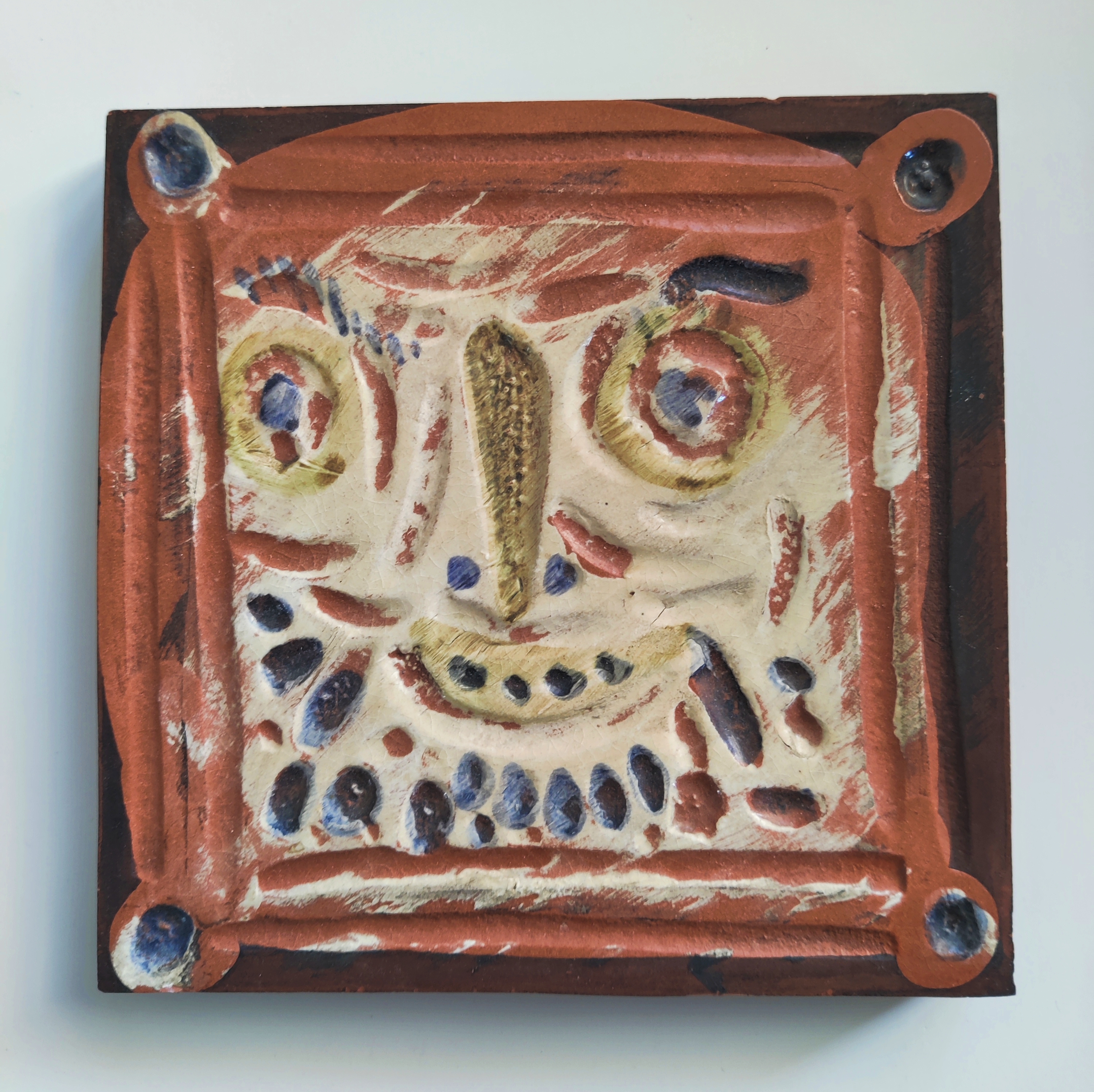 A ceramic tile with a face painted on it.