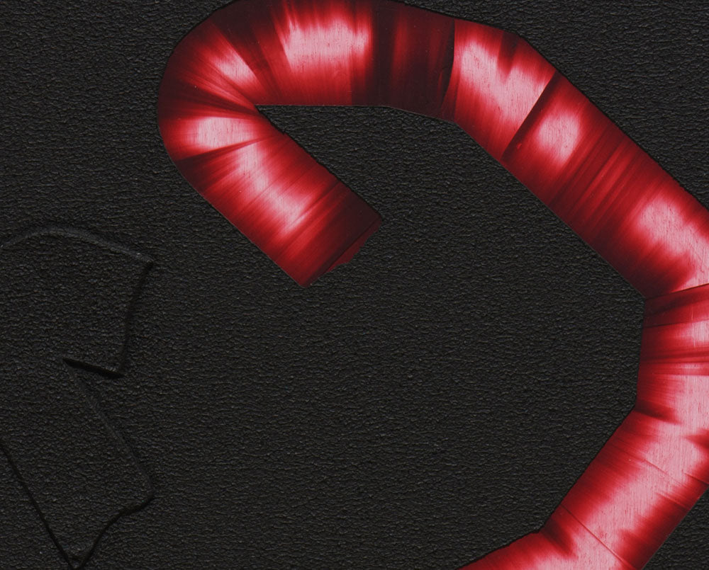 A red candy cane on a black background. 