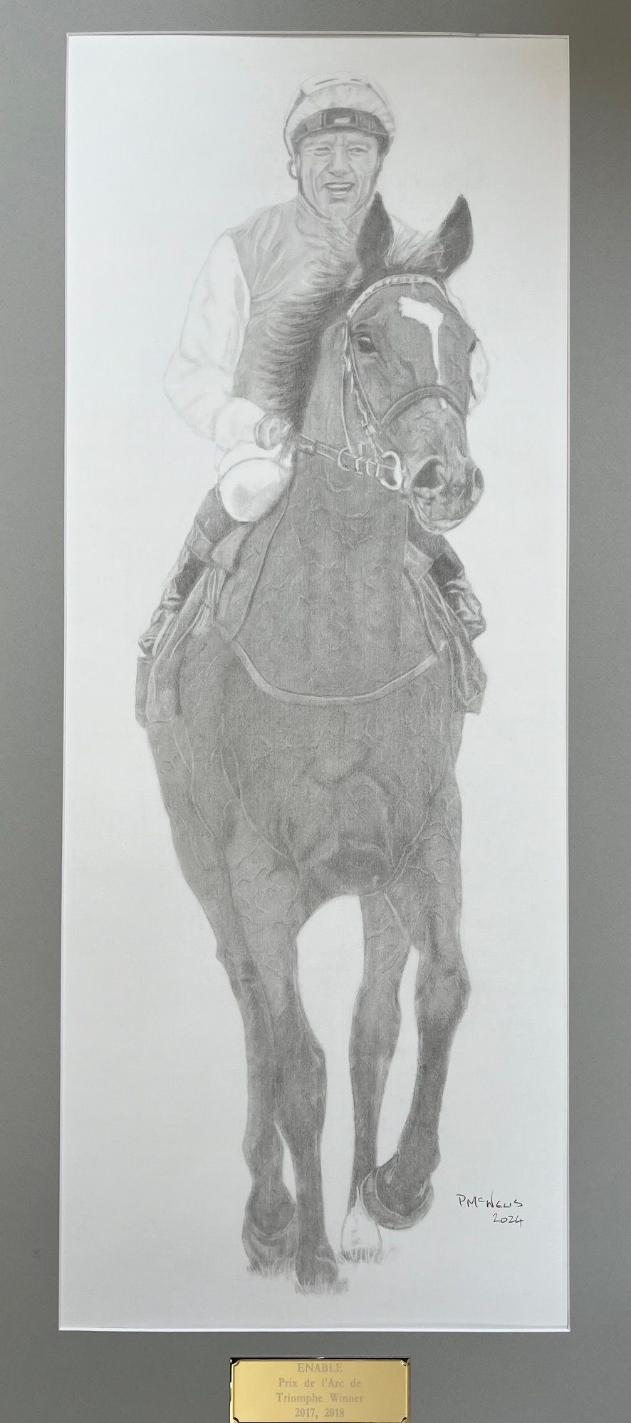 A detailed pencil portrait of a jockey riding a horse, framed with a commemorative plaque.