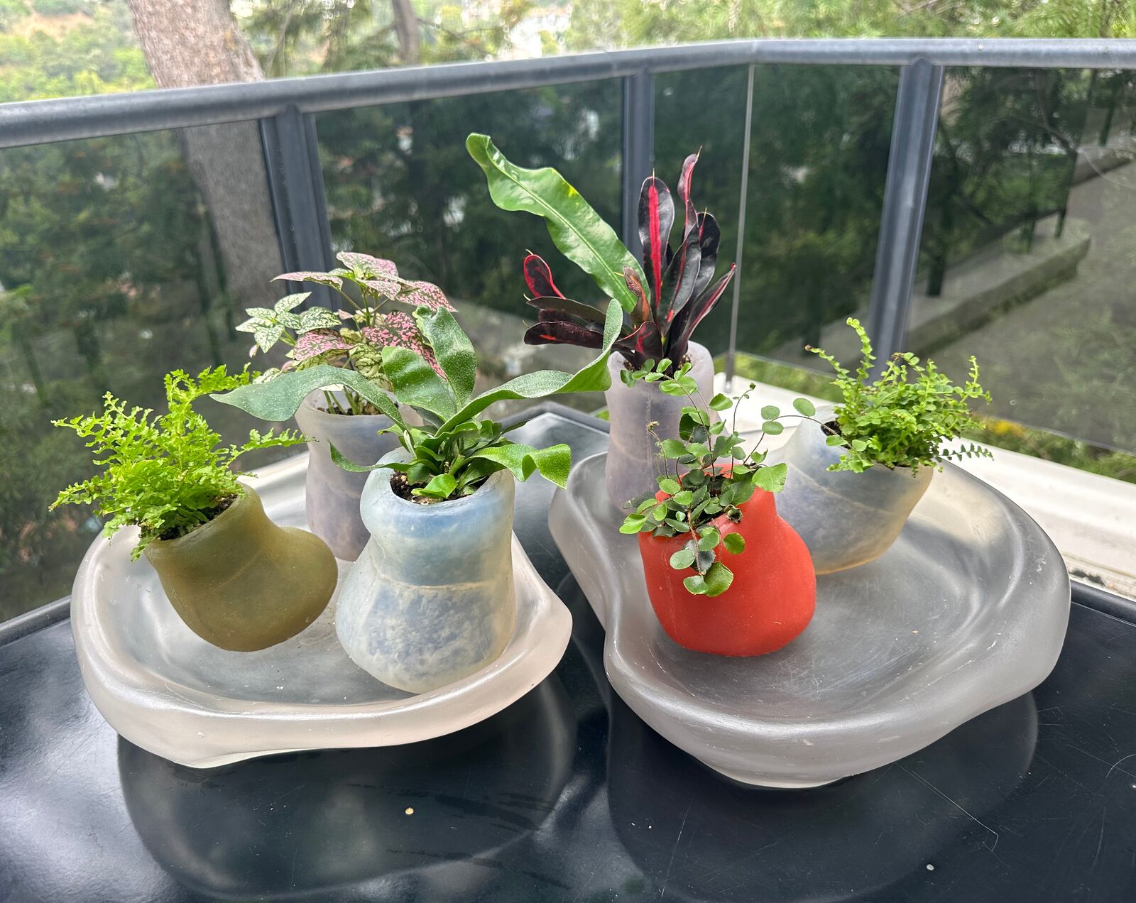 Artwork by Paula Hayes, Six mini silicone planters and two trays, Made of Planters: Cast silicone, Trays: Cast resin 