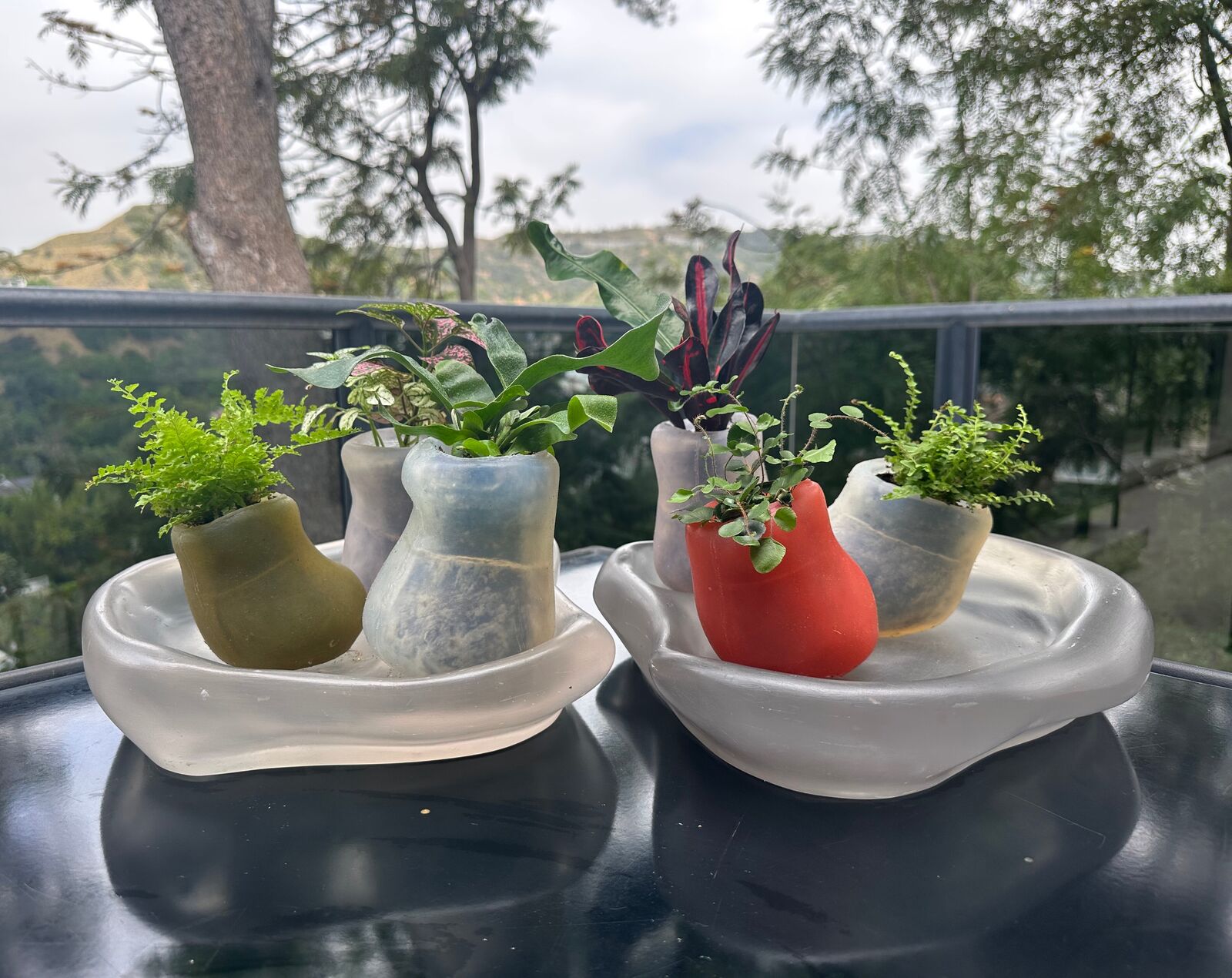 Artwork by Paula Hayes, Six mini silicone planters and two trays, Made of Planters: Cast silicone, Trays: Cast resin 