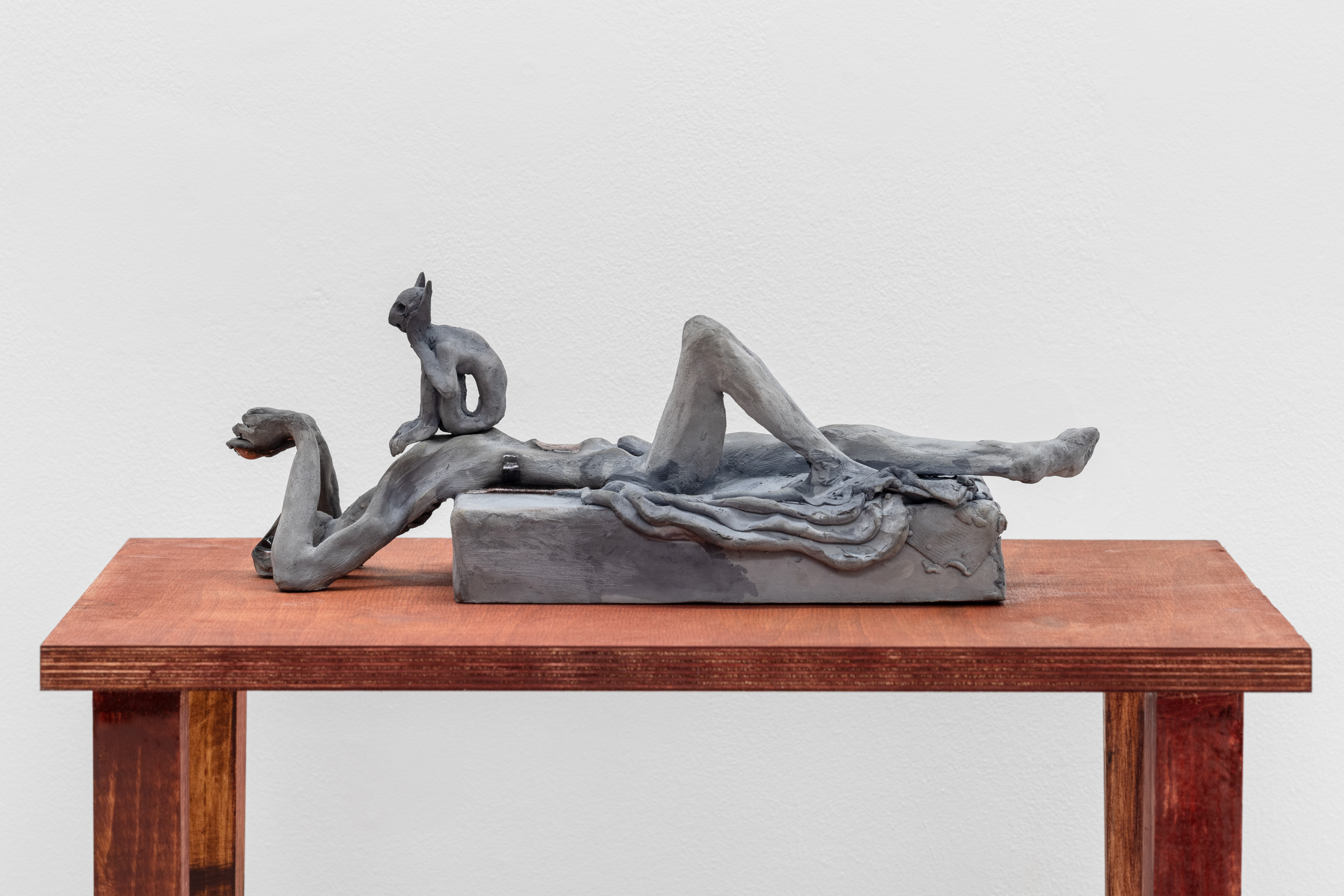 A sculpture of a woman laying on a wooden table.