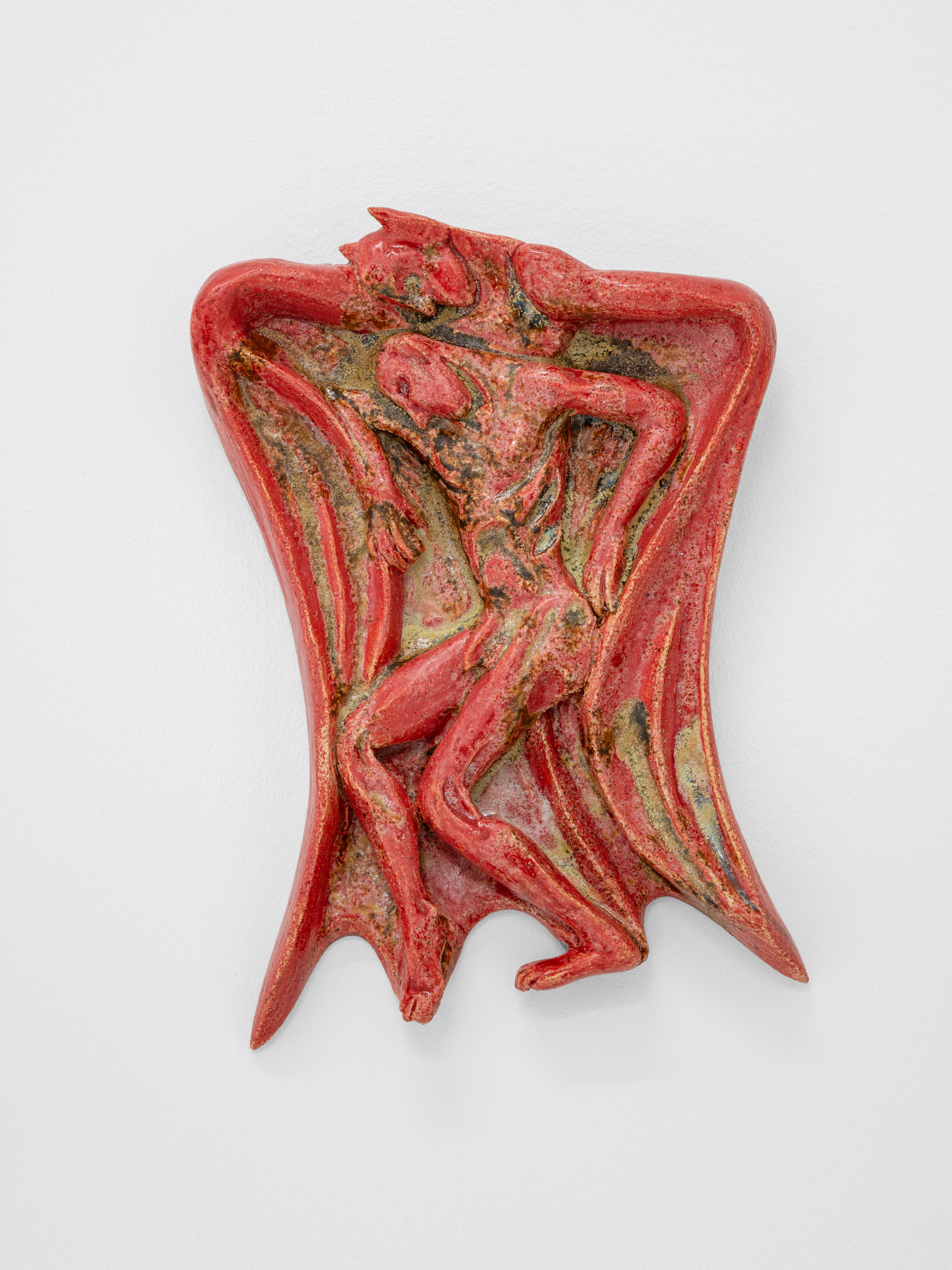 A red and green sculpture of a woman on a white surface.