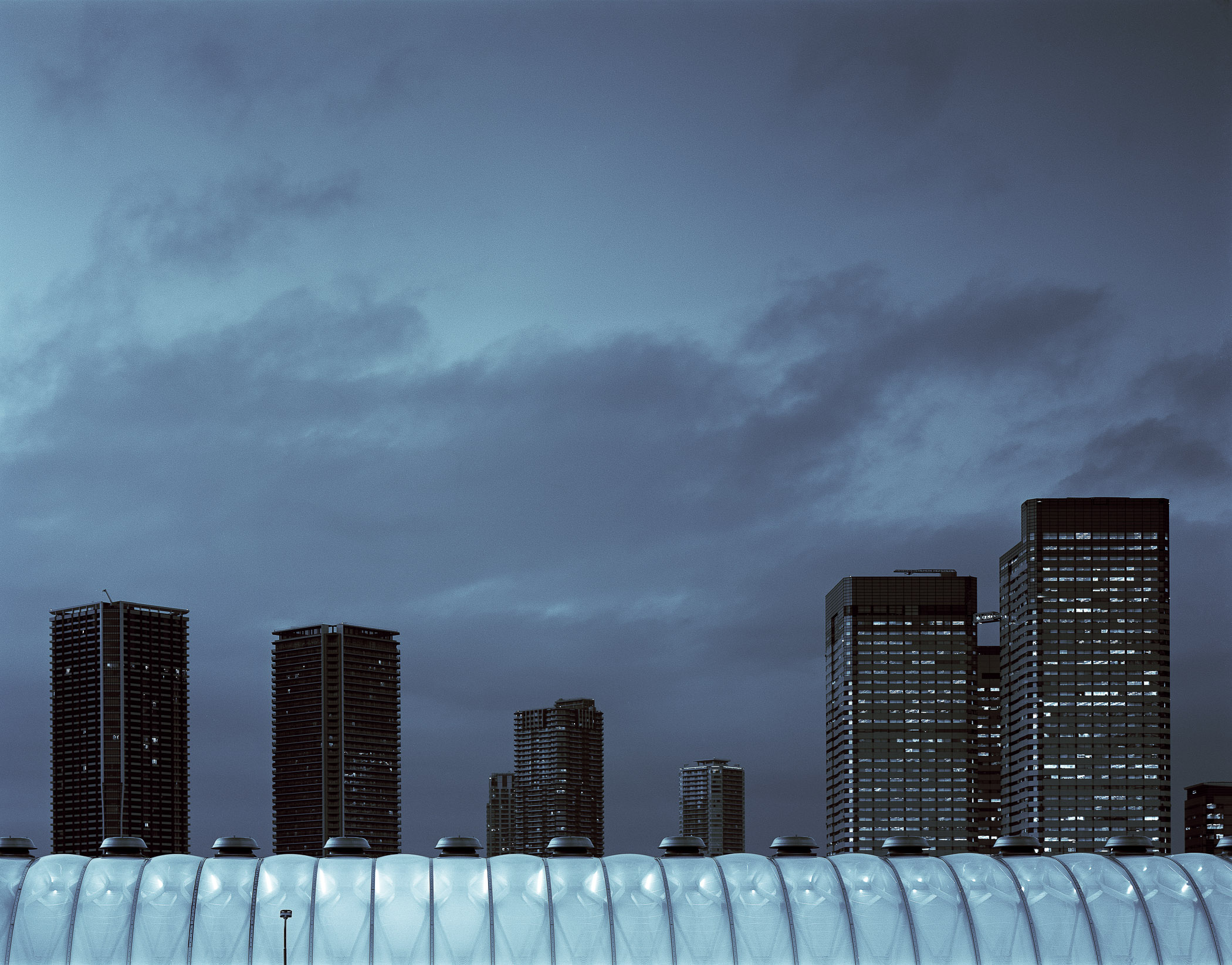 A group of tall buildings in a city under a cloudy sky.