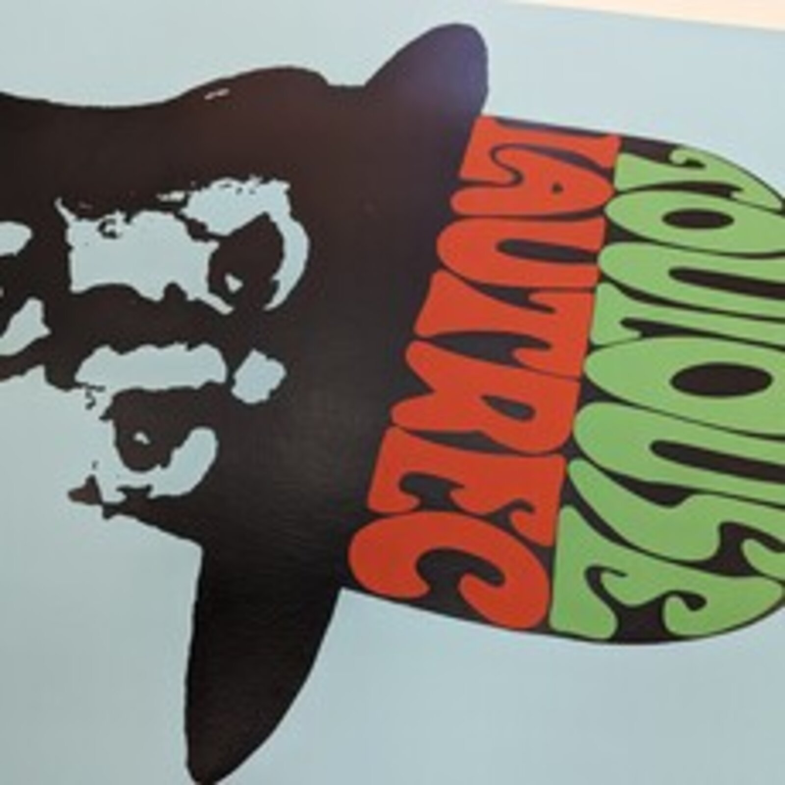 A bold graphic portrait of a bearded figure in silhouette against a light blue background, wearing a hat filled with colorful text.
