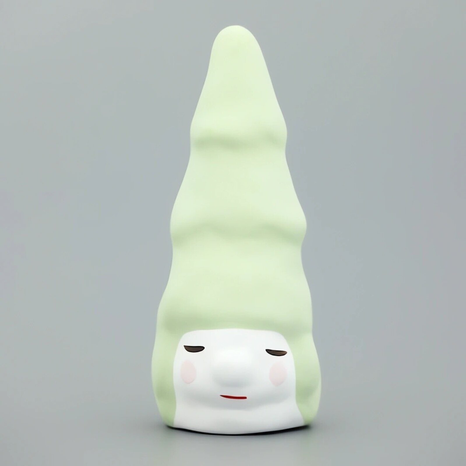 A whimsical ceramic figure with a tall, pointed green head and a serene white face.