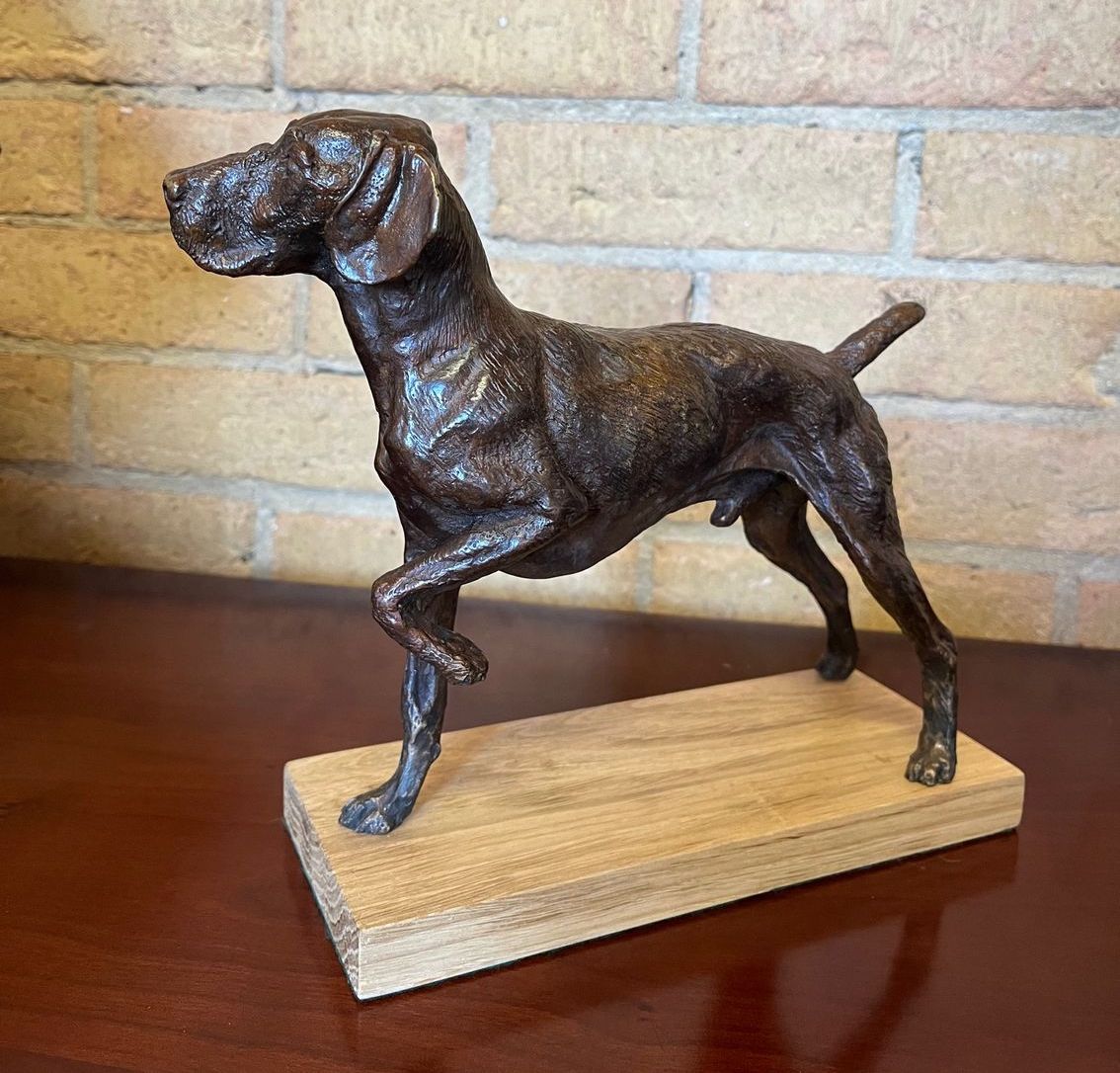 A bronze statue of a dog on a wooden base.