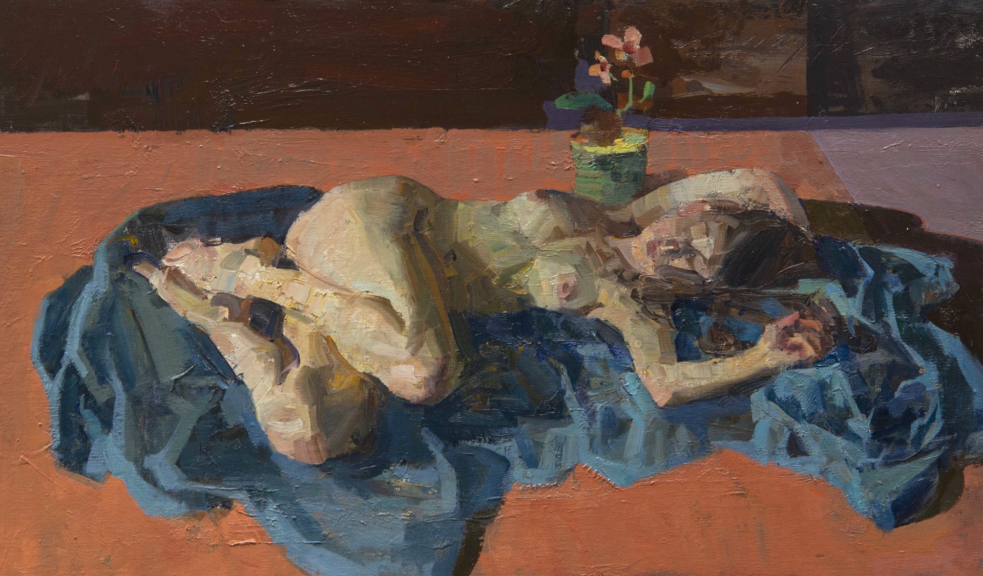 A figure rests on a blue cloth in a still life arrangement with a vase of flowers.