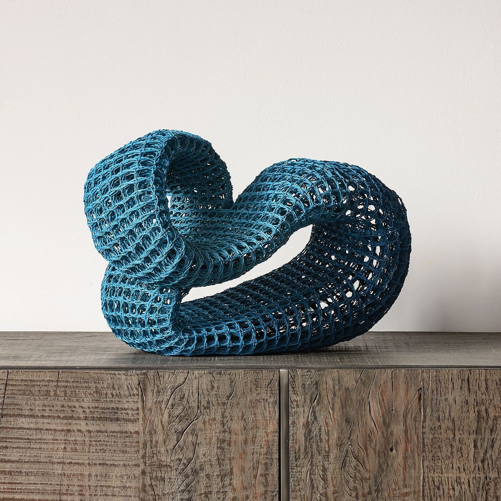 A blue sculpture on a wooden table on a hardwood floor.