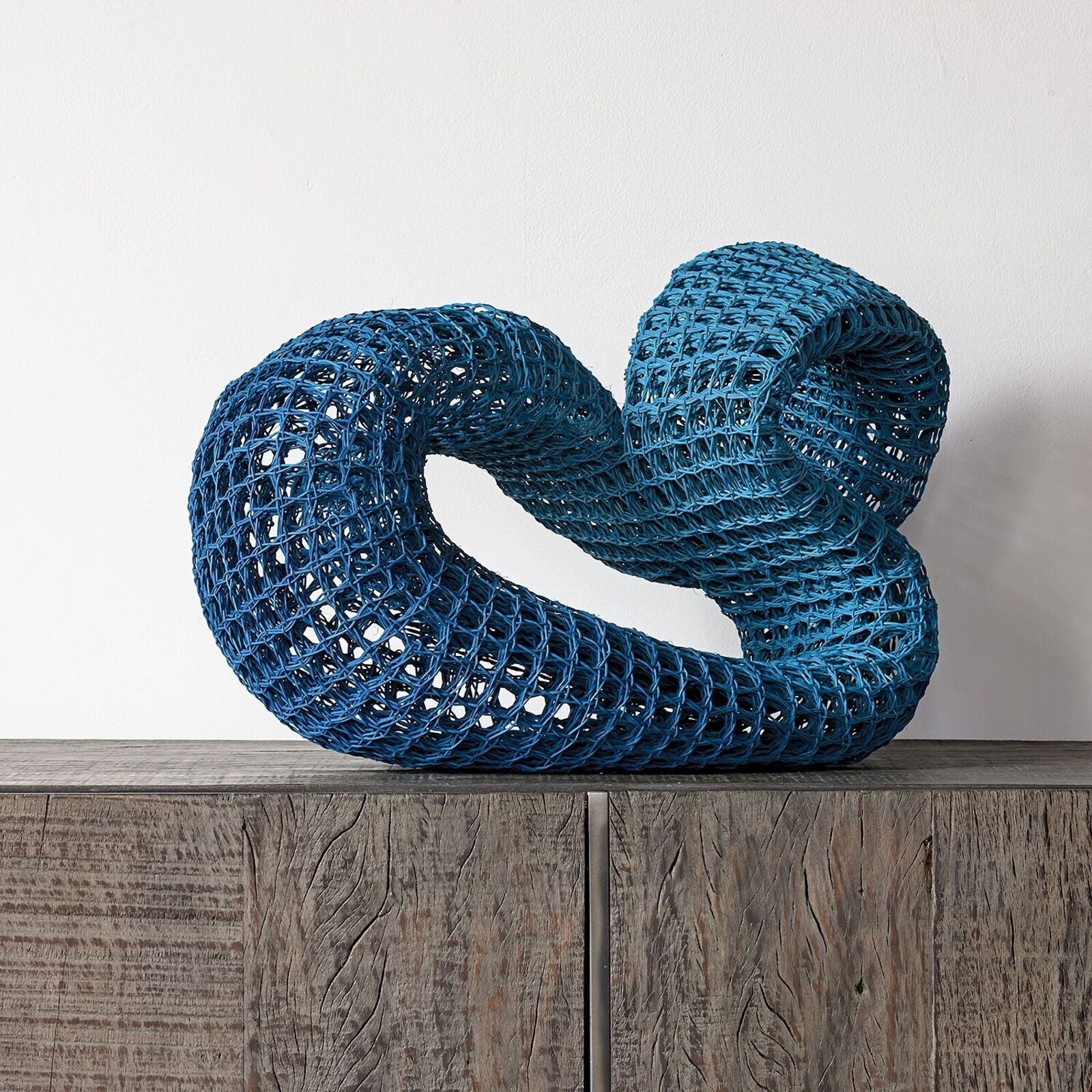 A blue sculpture on a wooden table on a hardwood floor.