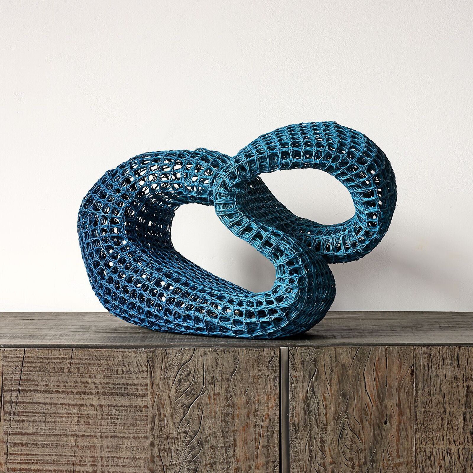 A blue sculpture on a wooden table on a hardwood floor.