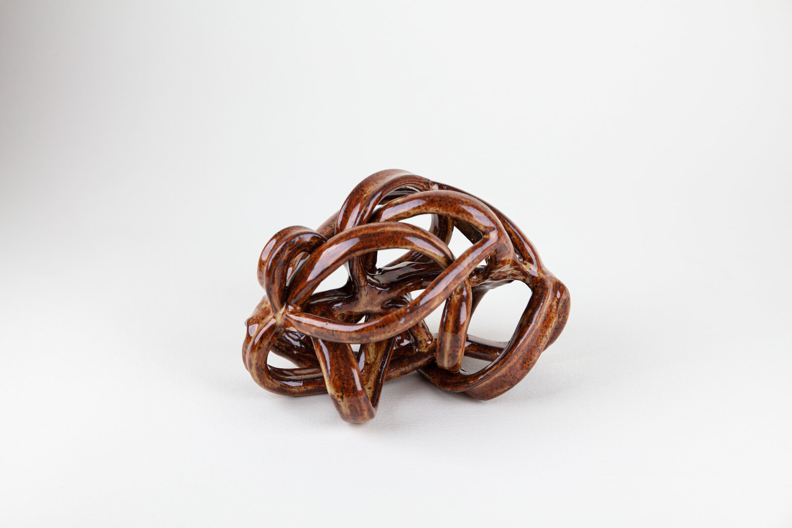 A brown sculpture of a knot on a white surface.