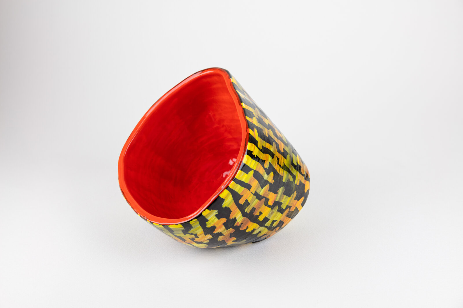 A red and yellow bowl sitting on top of a white surface.