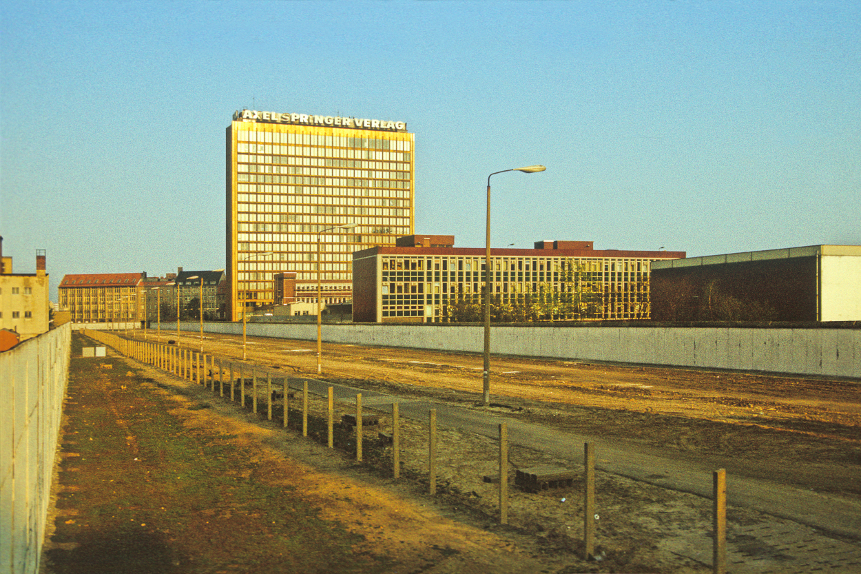 A view of a city with a fence and a building in the background.
