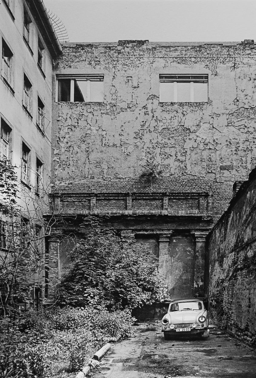 A car is parked in an alleyway next to an old building.