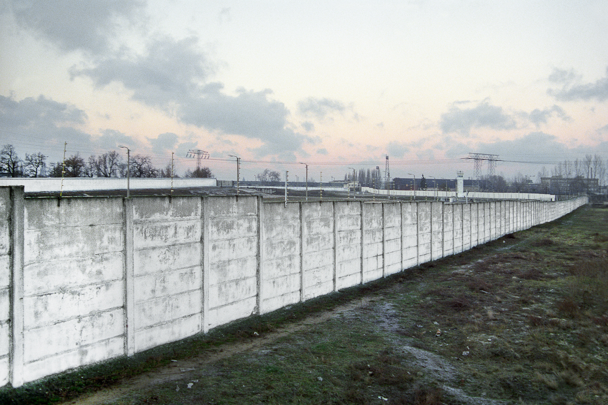 A large concrete wall in the middle of a grassy field.