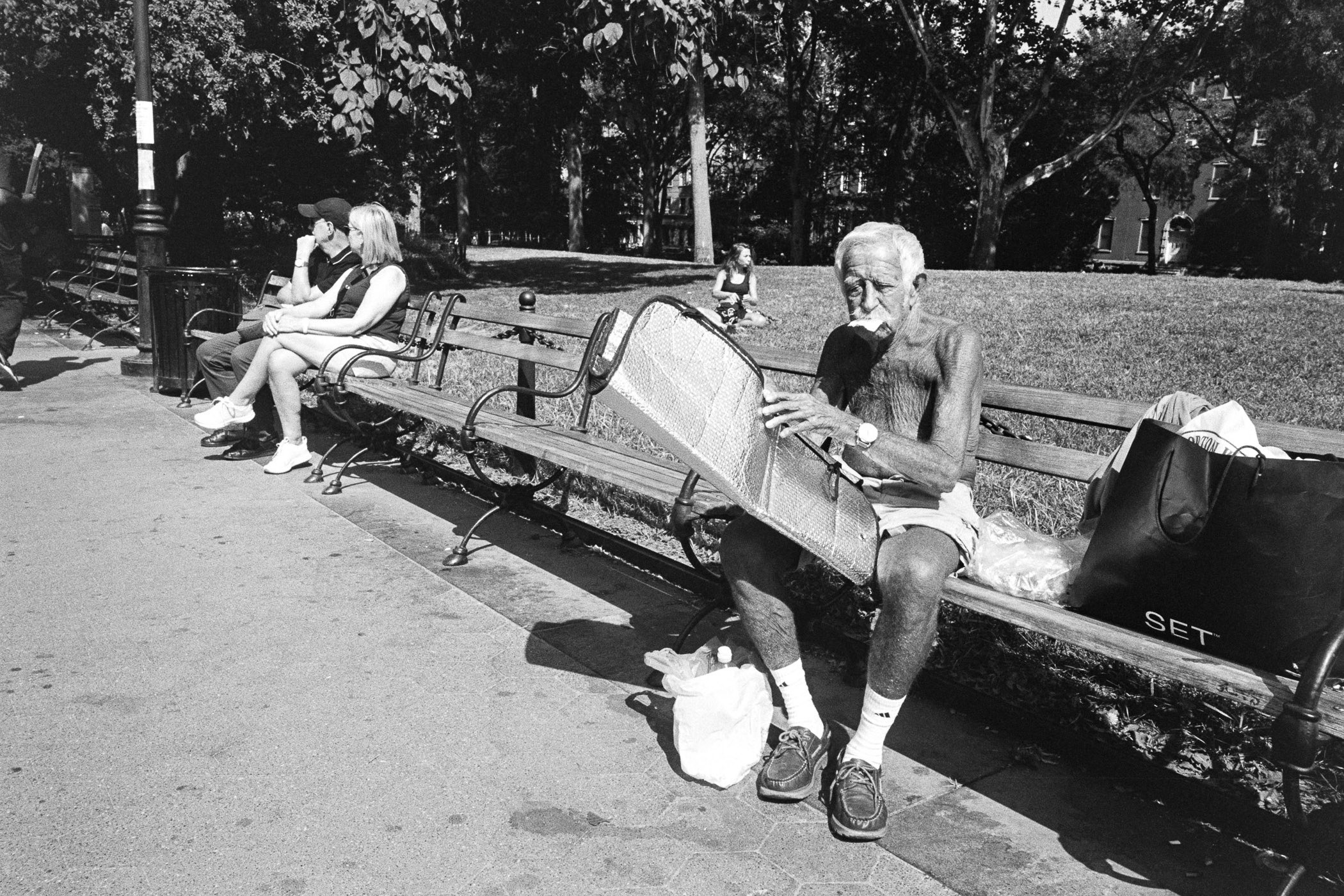 A man sitting on a park bench reading a newspaper.