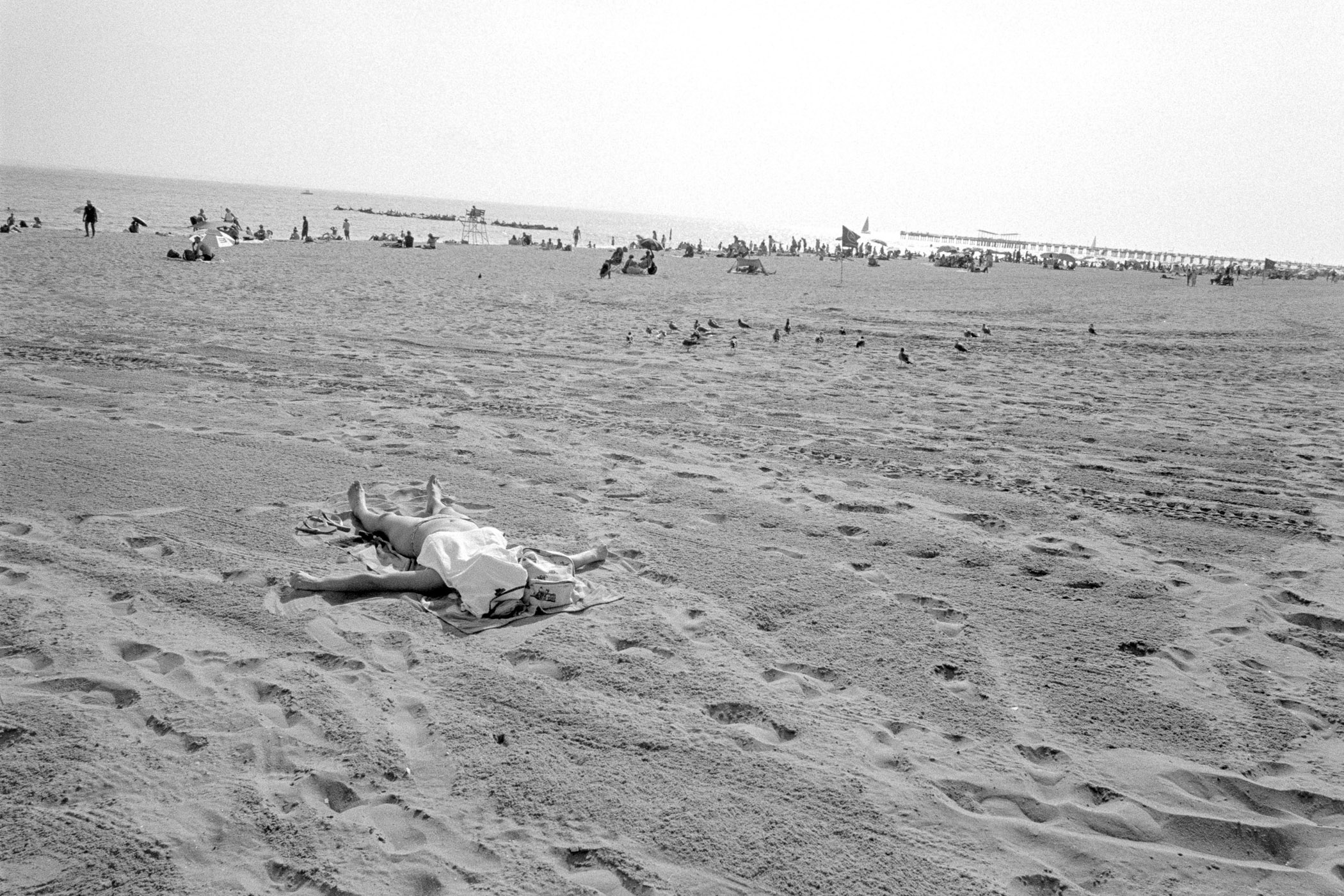 A person laying on a beach with a towel on the sand.