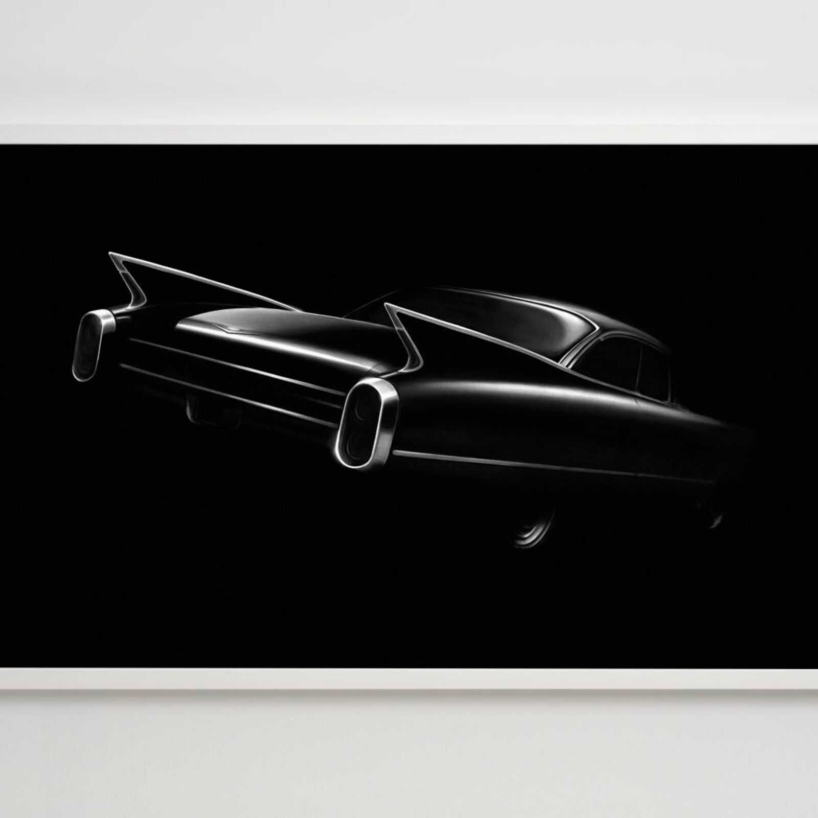 A black and white photo of a classic car on a wall.