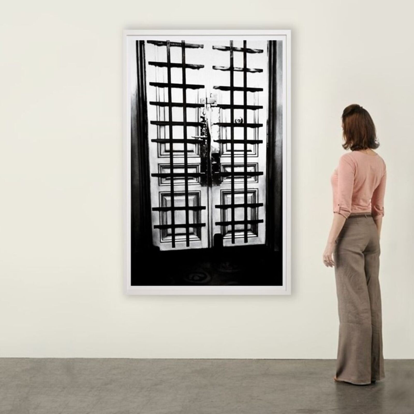 A black and white photo of a door with bars on it.