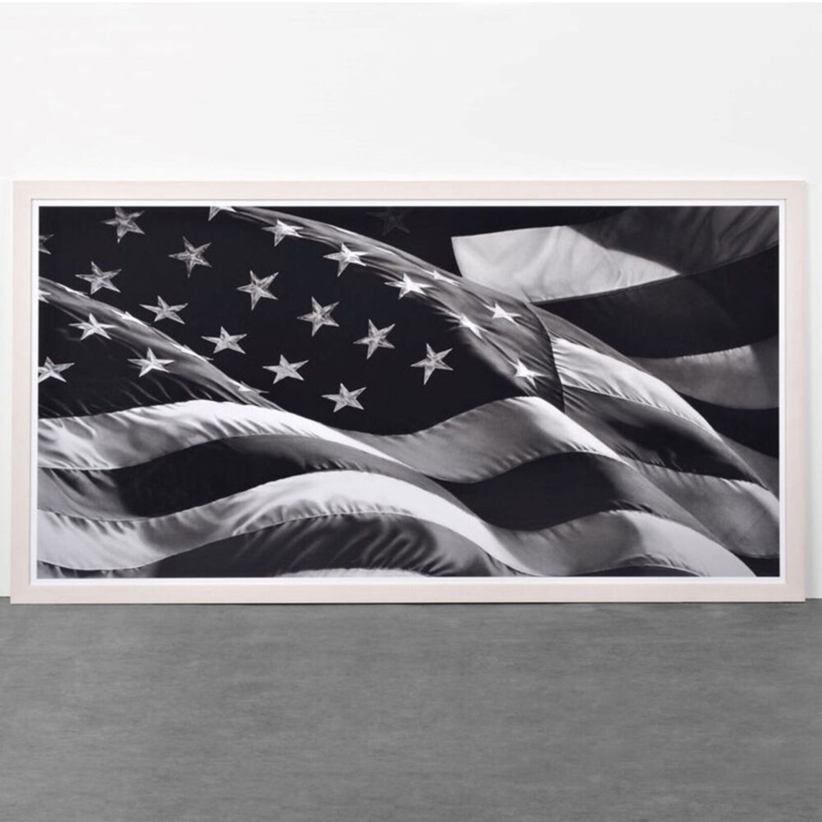A black and white framed print of a waving flag with stars and stripes.