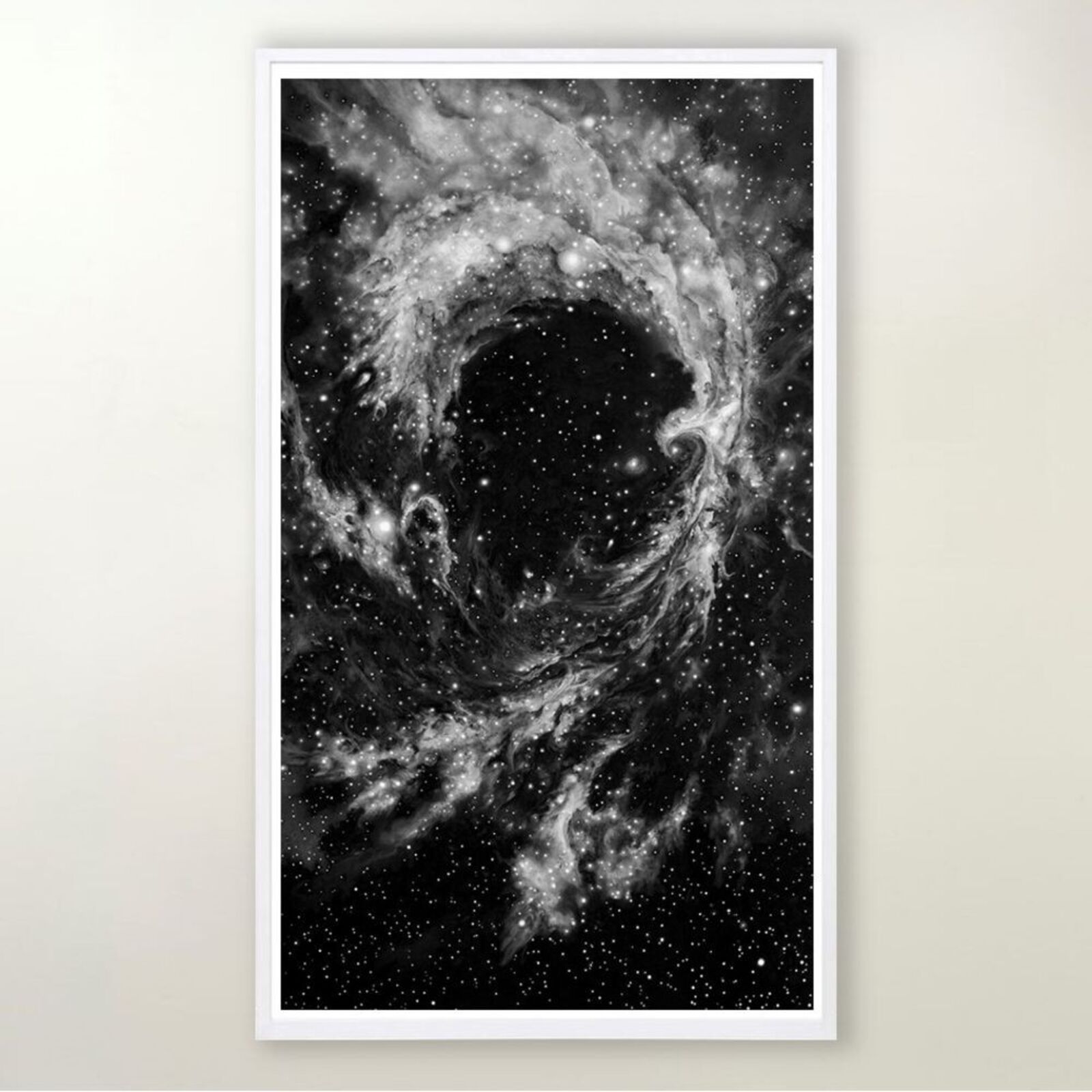 A framed black-and-white print of a swirling cosmic nebula against a minimalist interior wall.