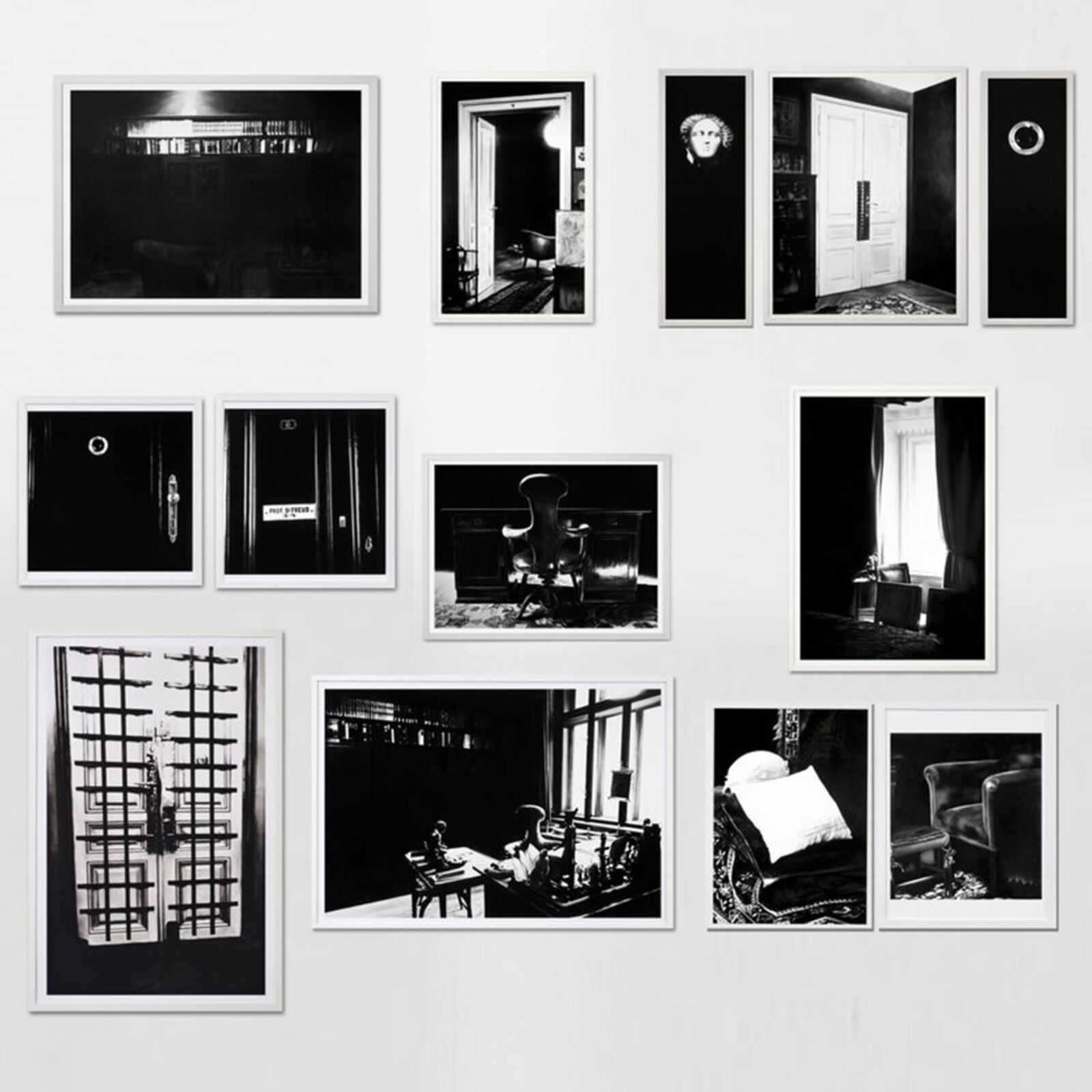 A gallery wall of black and white framed photographs showcasing interior details.