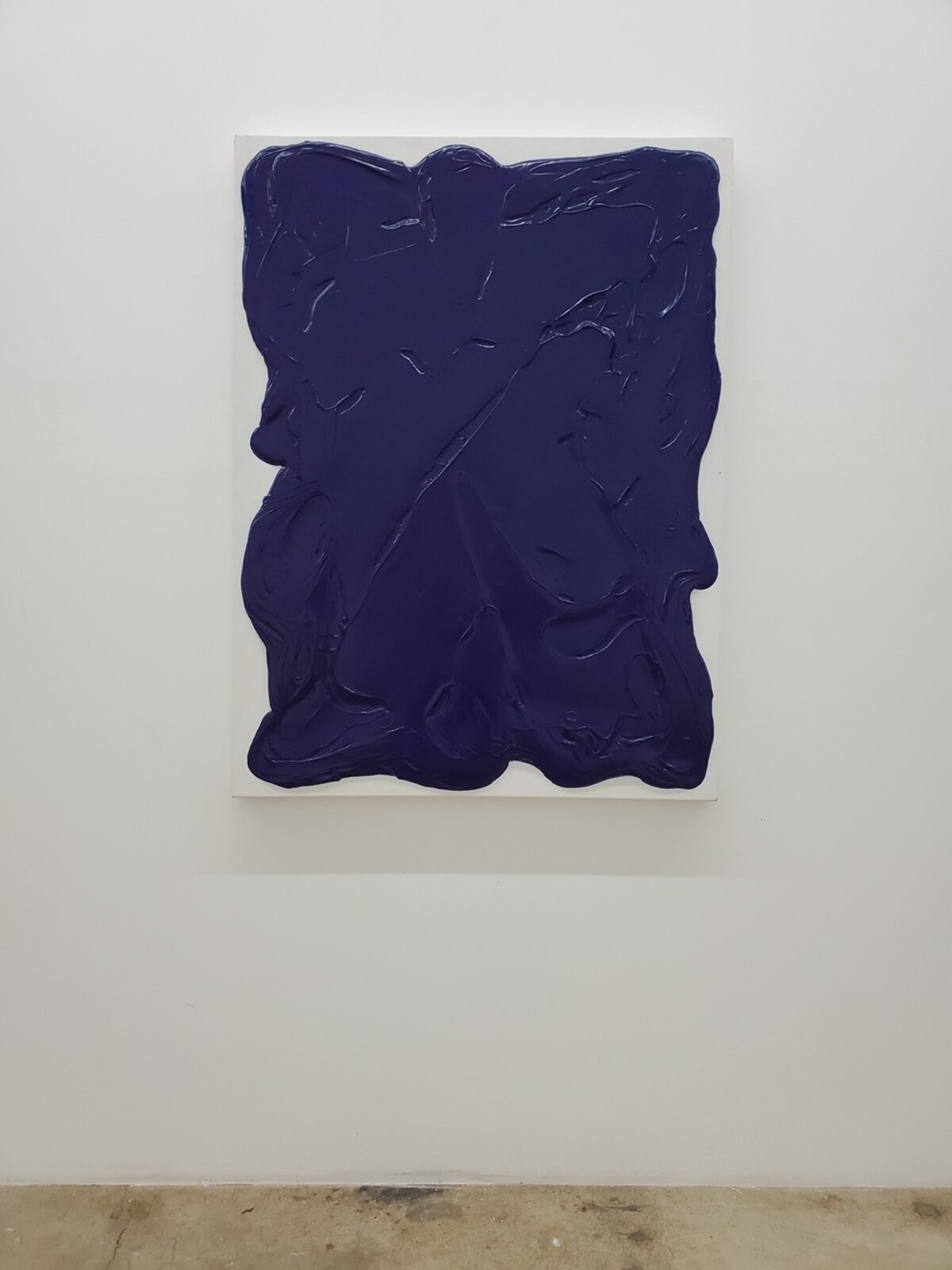 A thick, dark blue abstract form on a white canvas.