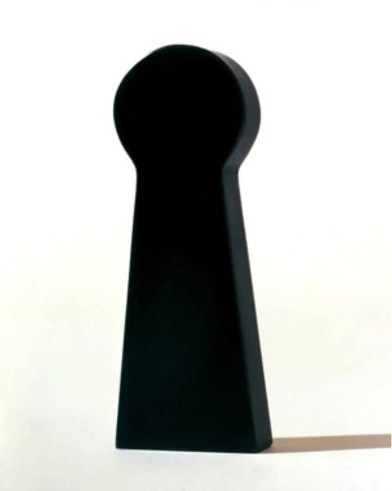 A minimalist black sculpture shaped like a keyhole against a stark white background.