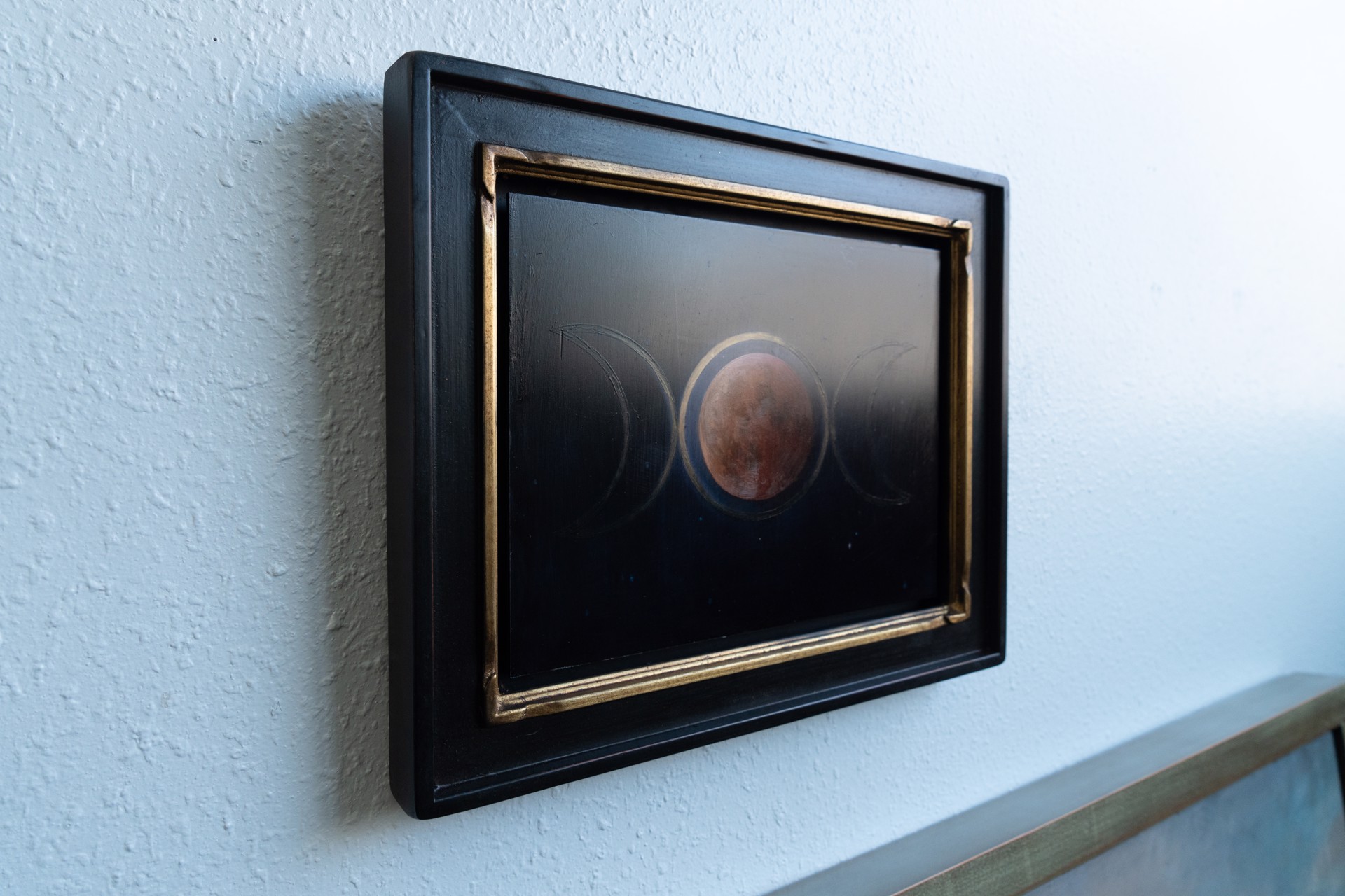 A painting of three phases of the moon in the night sky.