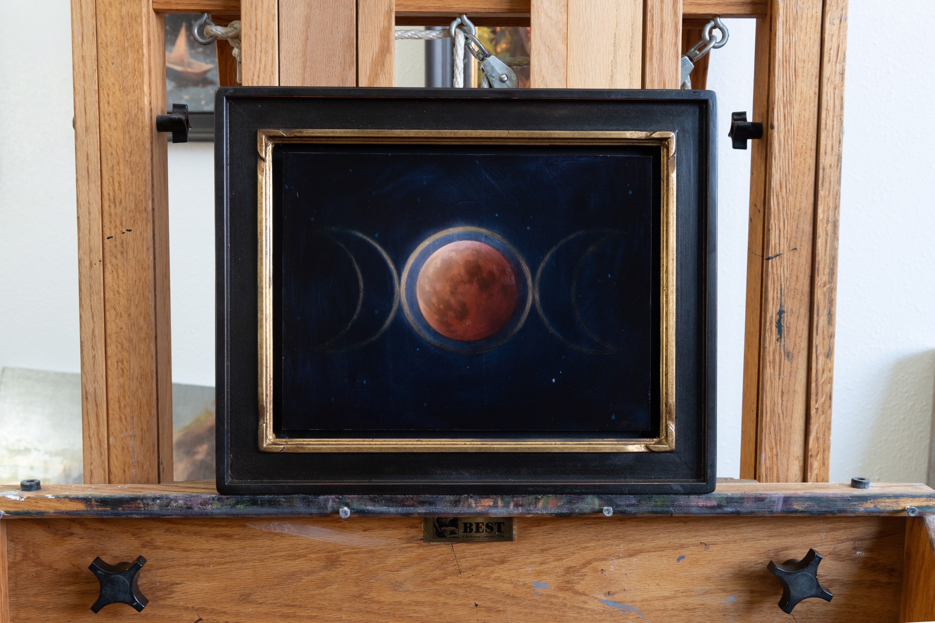 A painting of three phases of the moon in the night sky.