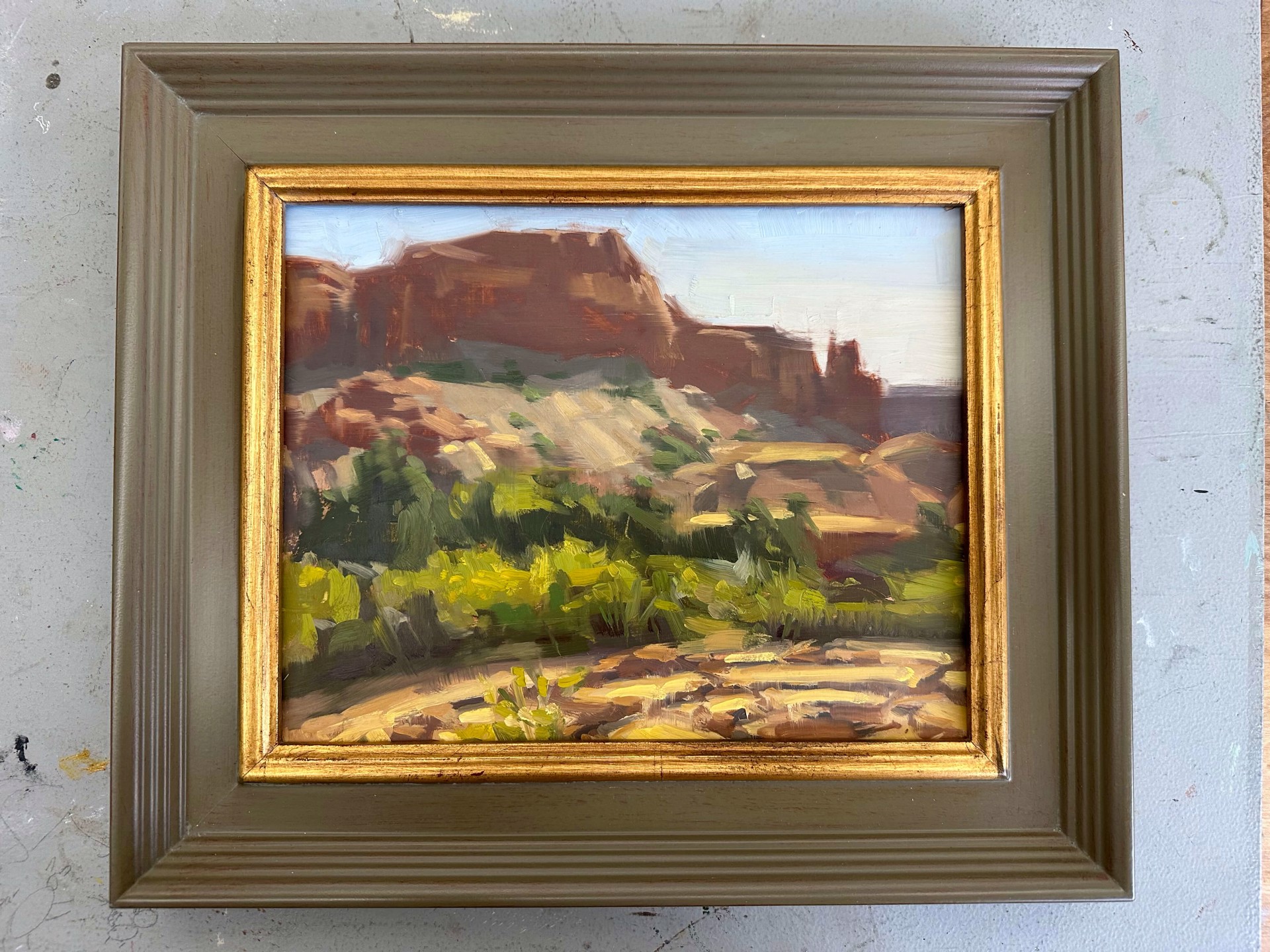 A painting of a desert landscape with a mountain in the background.