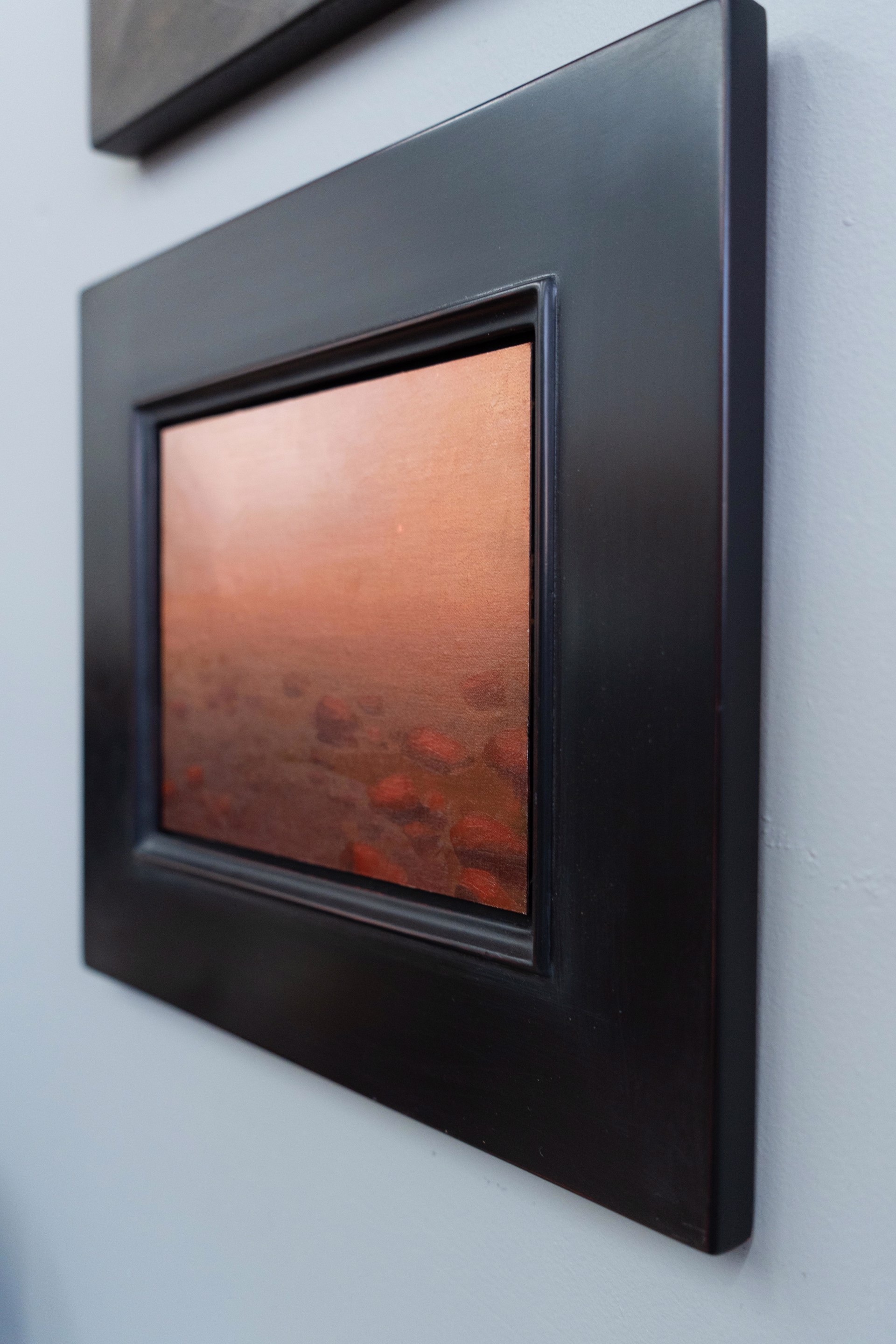 A hazy, atmospheric landscape featuring a rocky shoreline under an orange sky.