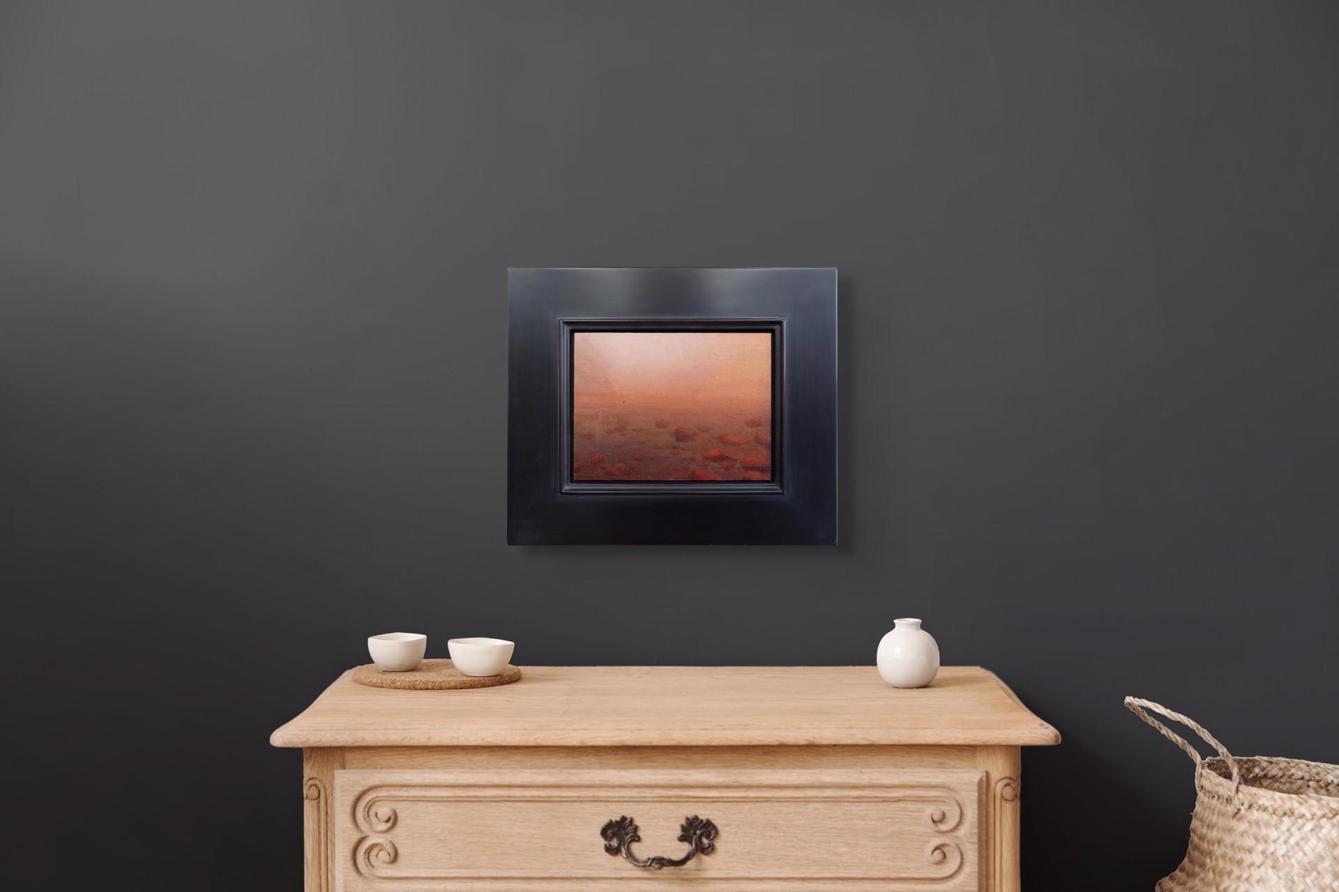 A hazy, atmospheric landscape featuring a rocky shoreline under an orange sky.