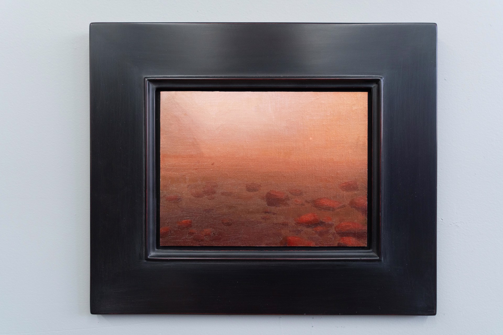 A hazy, atmospheric landscape featuring a rocky shoreline under an orange sky.