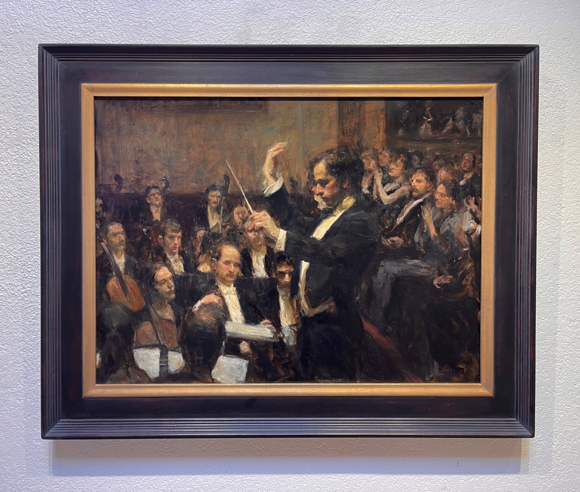 A conductor leads an orchestra in a warmly lit concert hall.