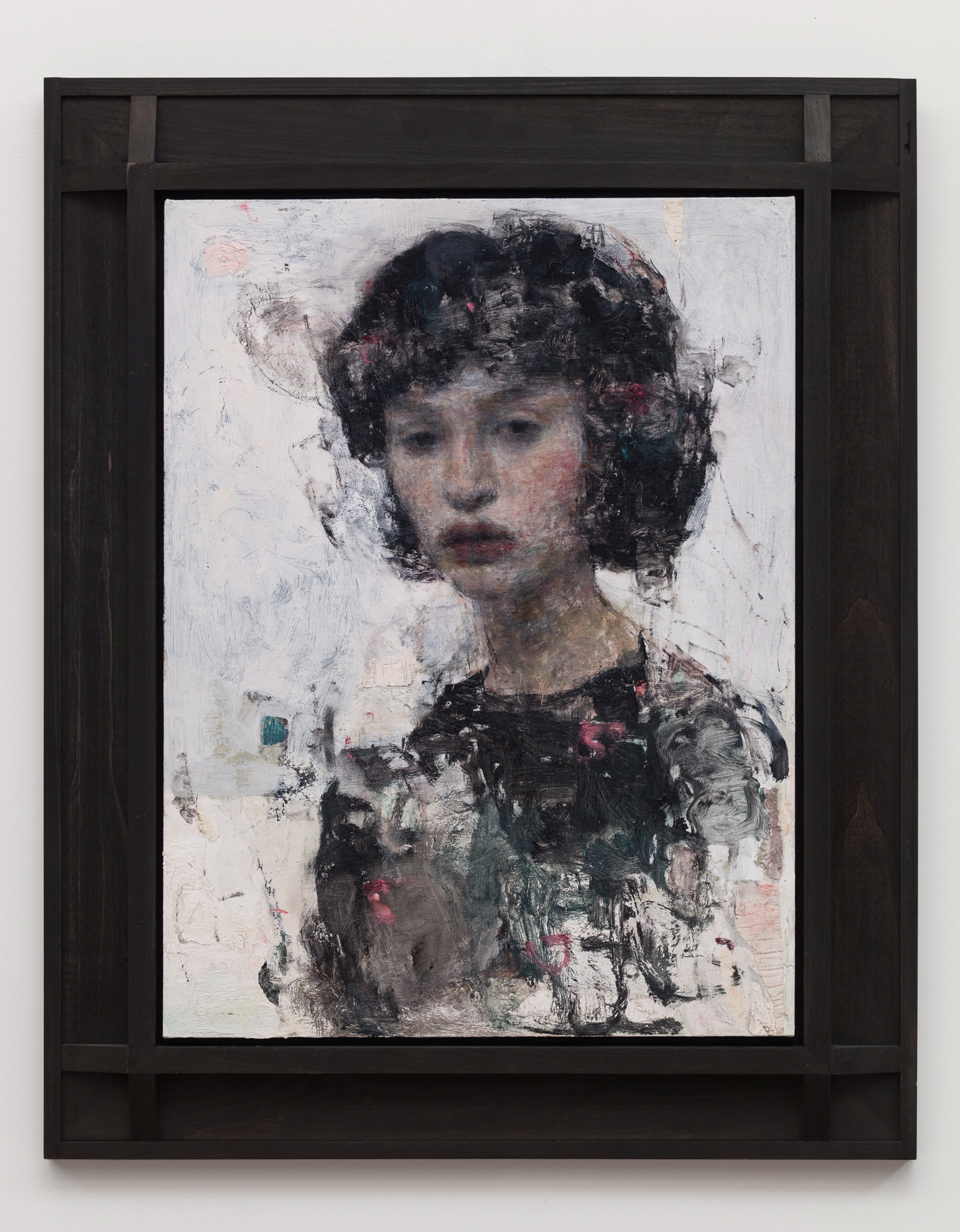 A moody portrait of a figure with dark, textured hair and a somber expression.