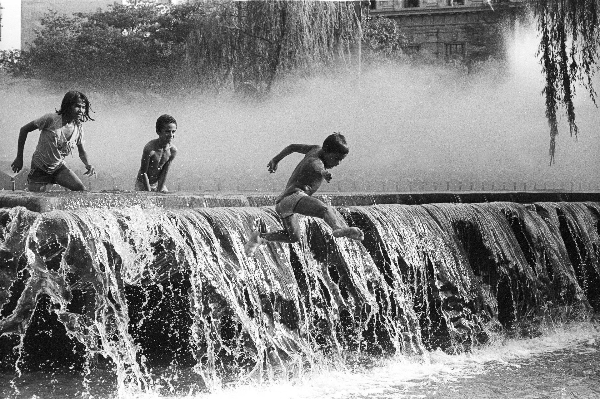 A group of children playing in a water fountain.