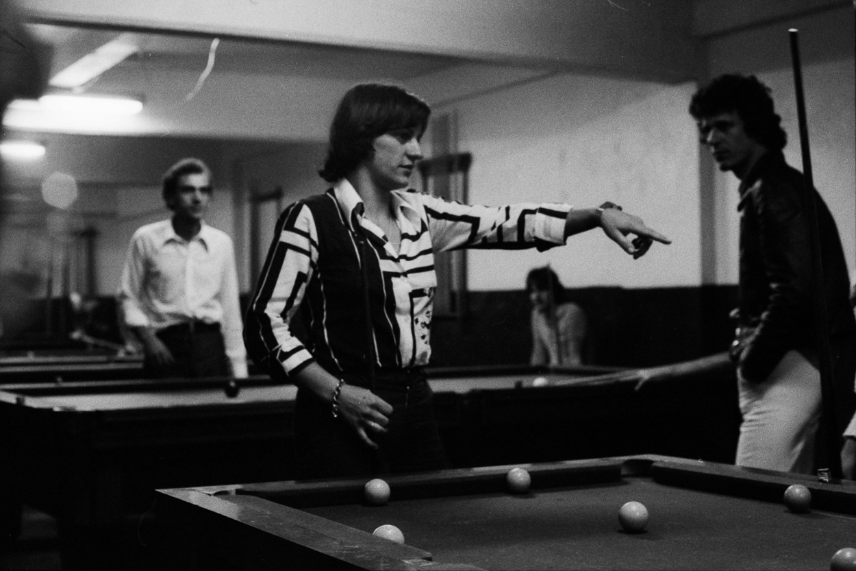 A group of people playing pool in a room.