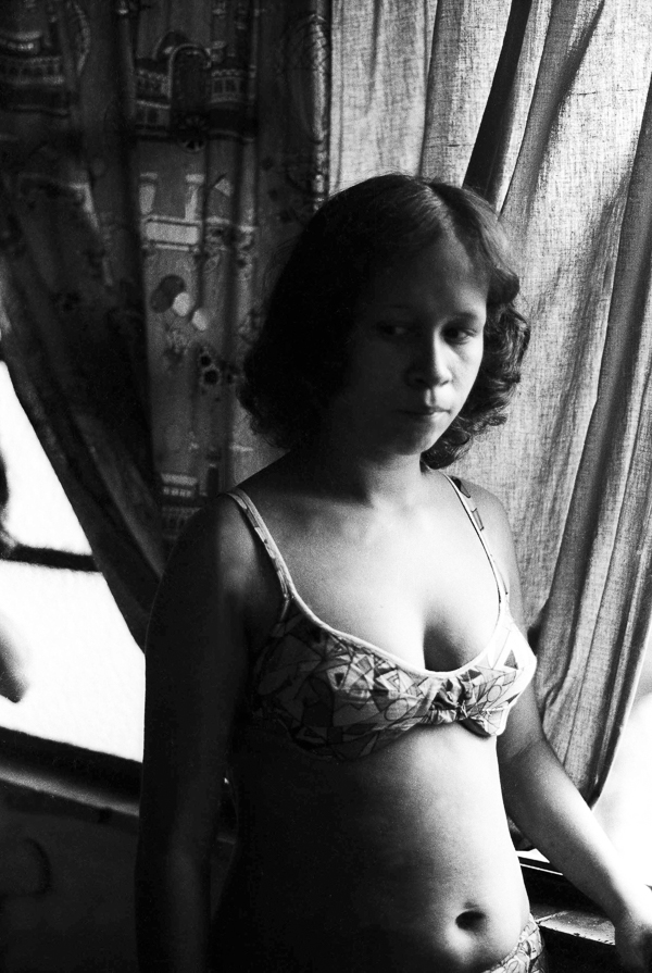 A young girl standing in front of a window.