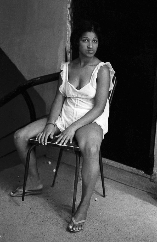 A woman sitting on a chair in a white dress.